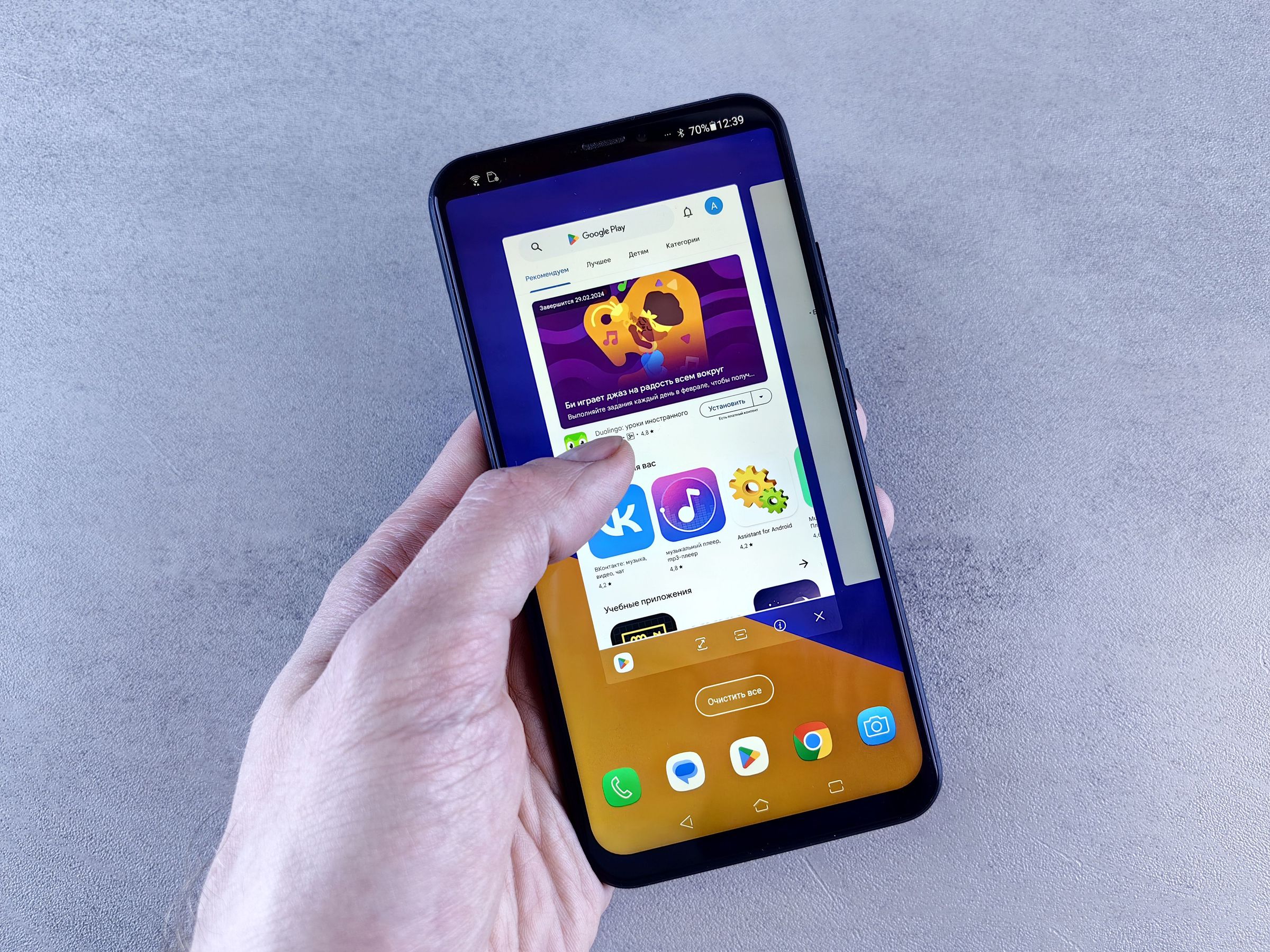Hand holding a phone displaying Google Play among open applications