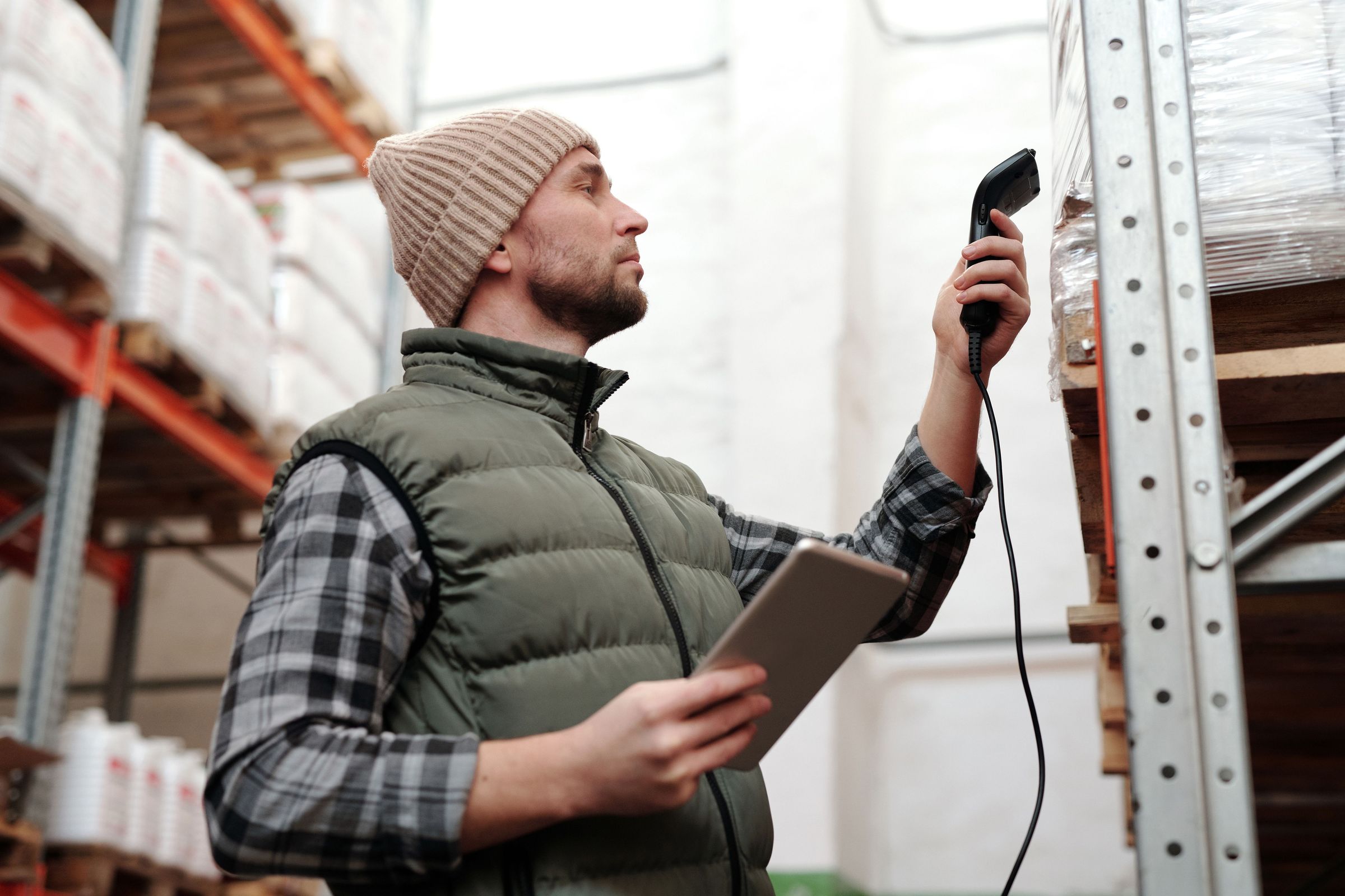 Worker aiming a barcode reader at goods on a warehouse rack