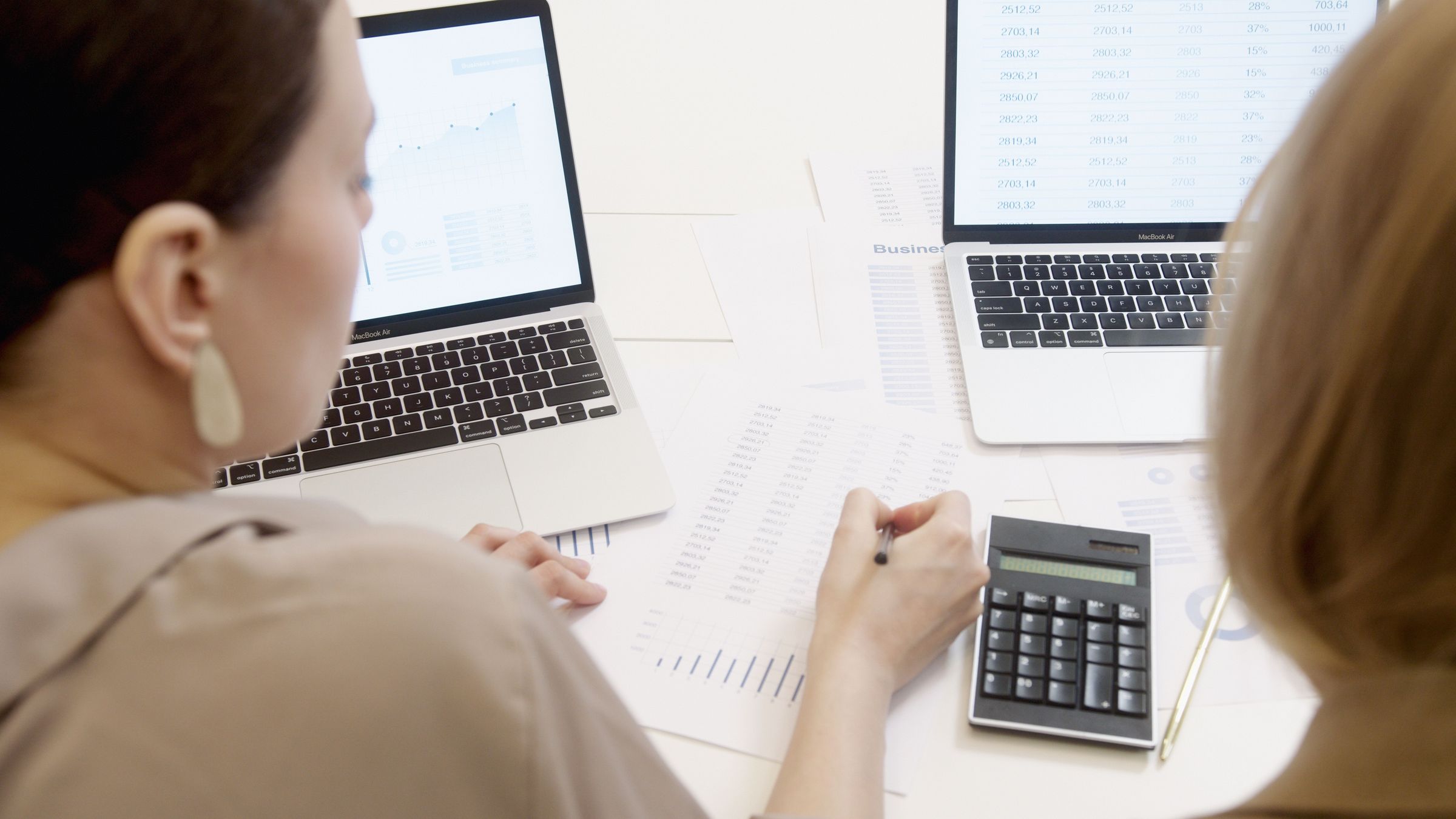 Reviewing printed tables and data on two laptops