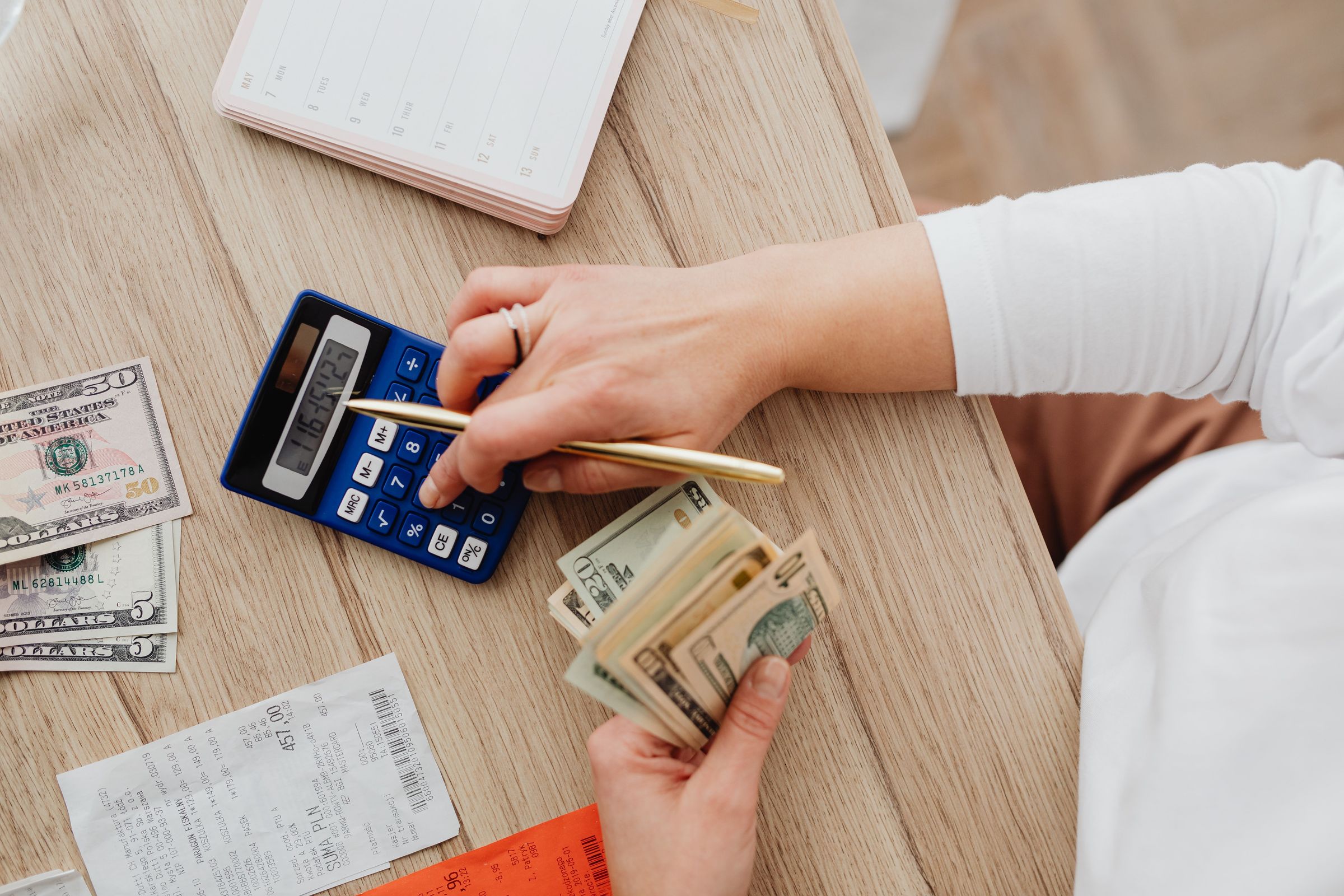 Counting dollar notes using a calculator beside receipts