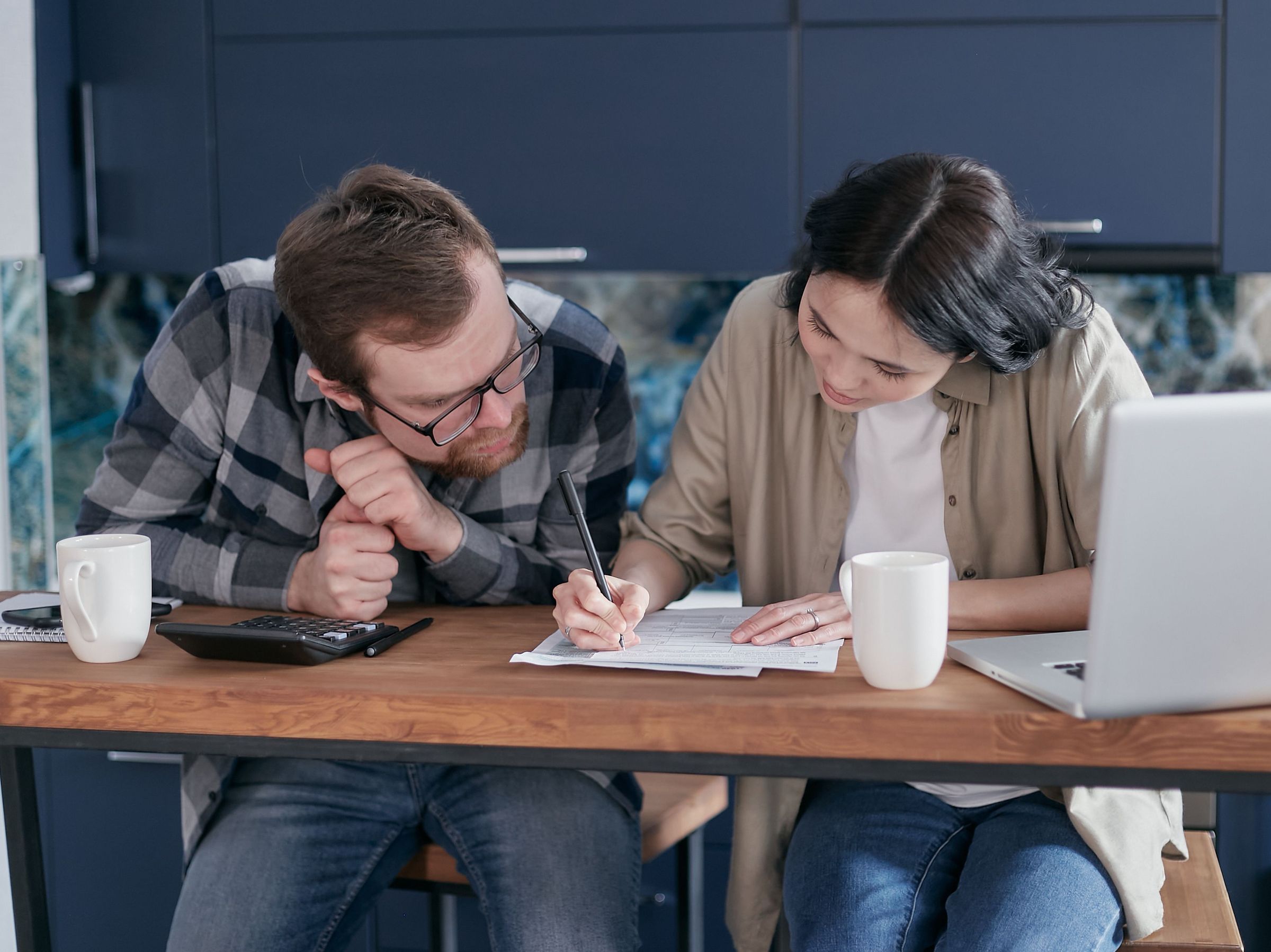 Real photograph of two people reviewing papers beside a calculator and laptop