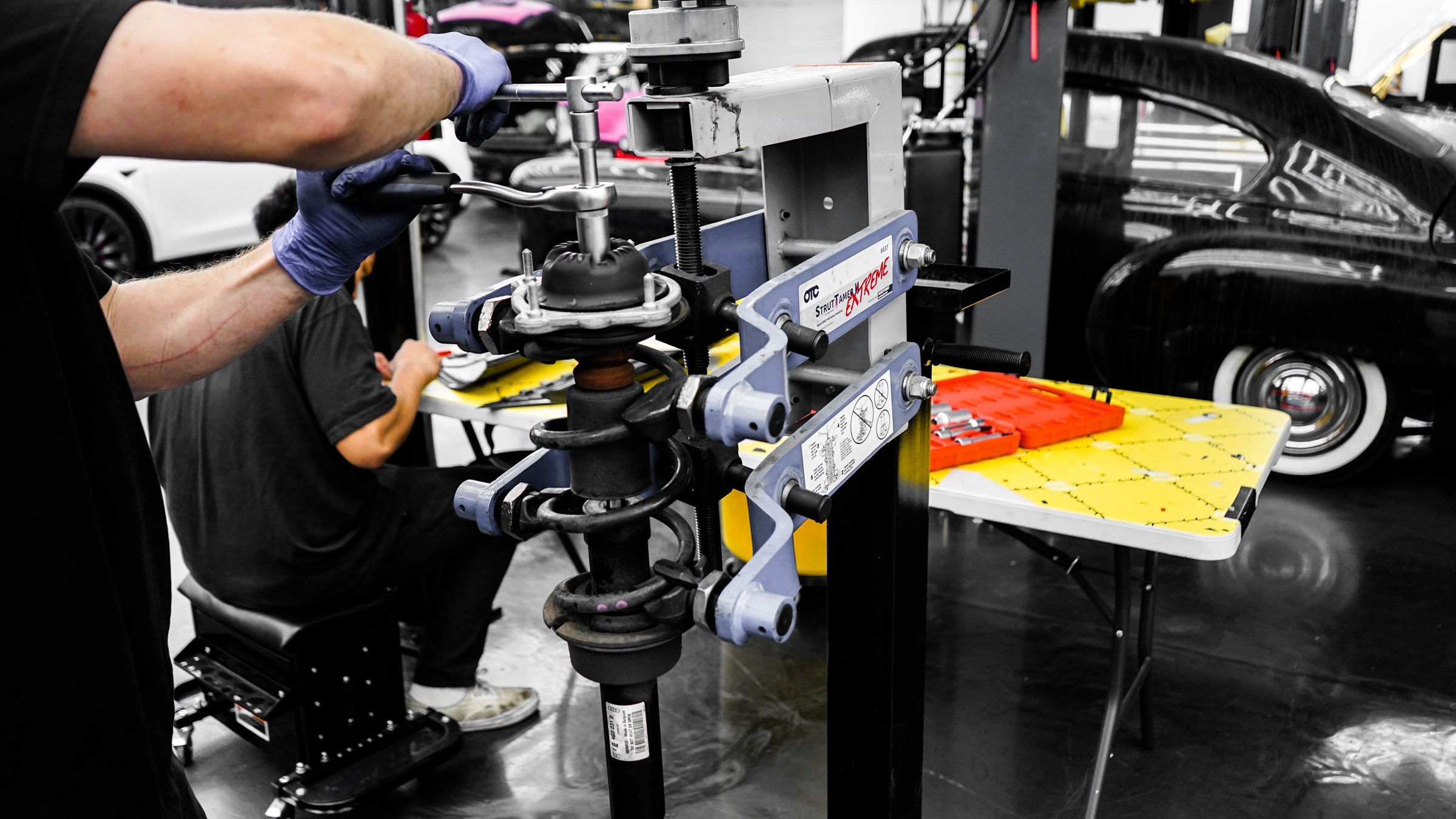 Workers using equipment to service a vehicle component inside a workshop