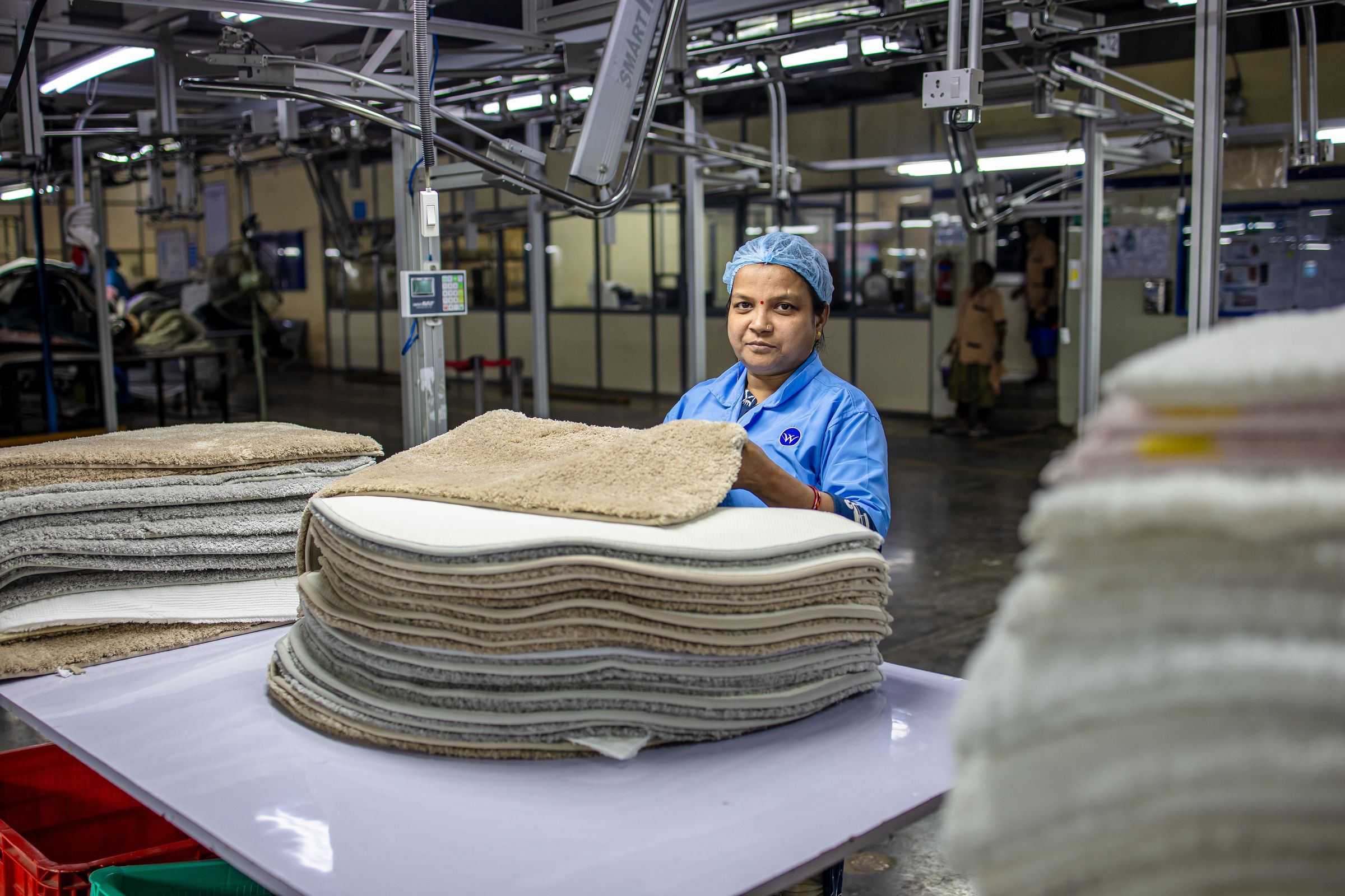 Worker handling stacked textile products in a factory