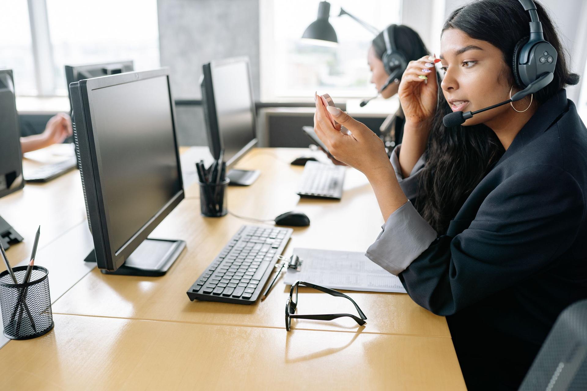 Arab woman in a headscarf using a laptop and headset in AI-assisted customer service