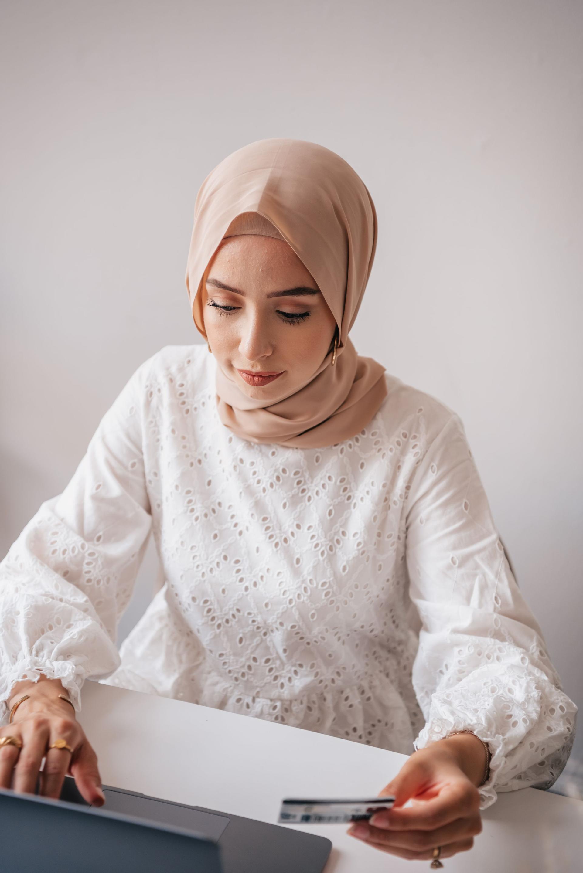 متسوقة عربية تستخدم بطاقة دفع وحاسوباً للتسوق الإلكتروني
