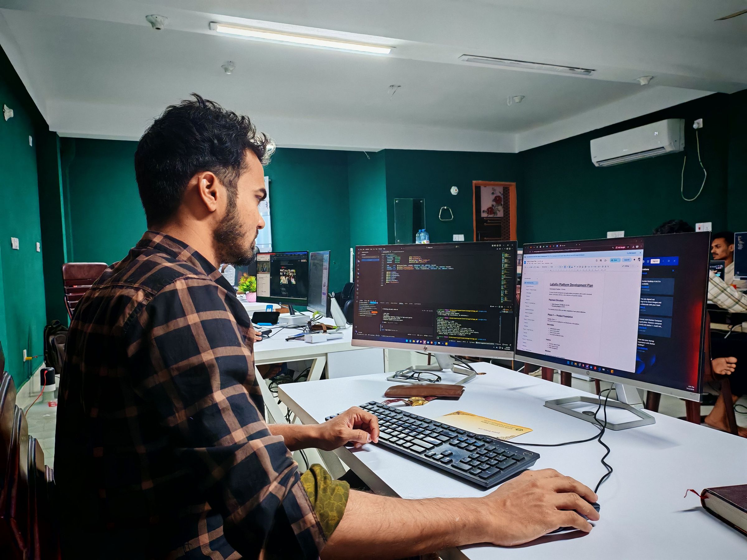 Developer using a keyboard and mouse beside code and planning screens