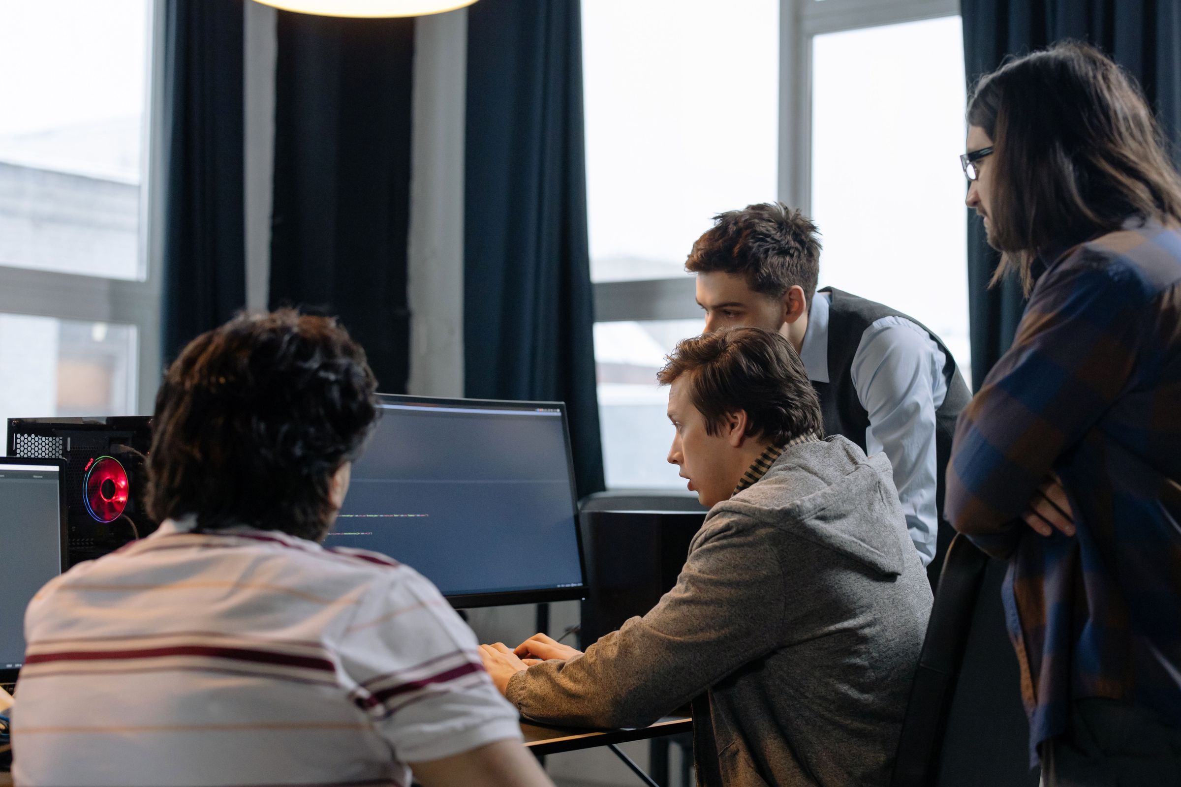 Team discussing software code visible on a computer screen
