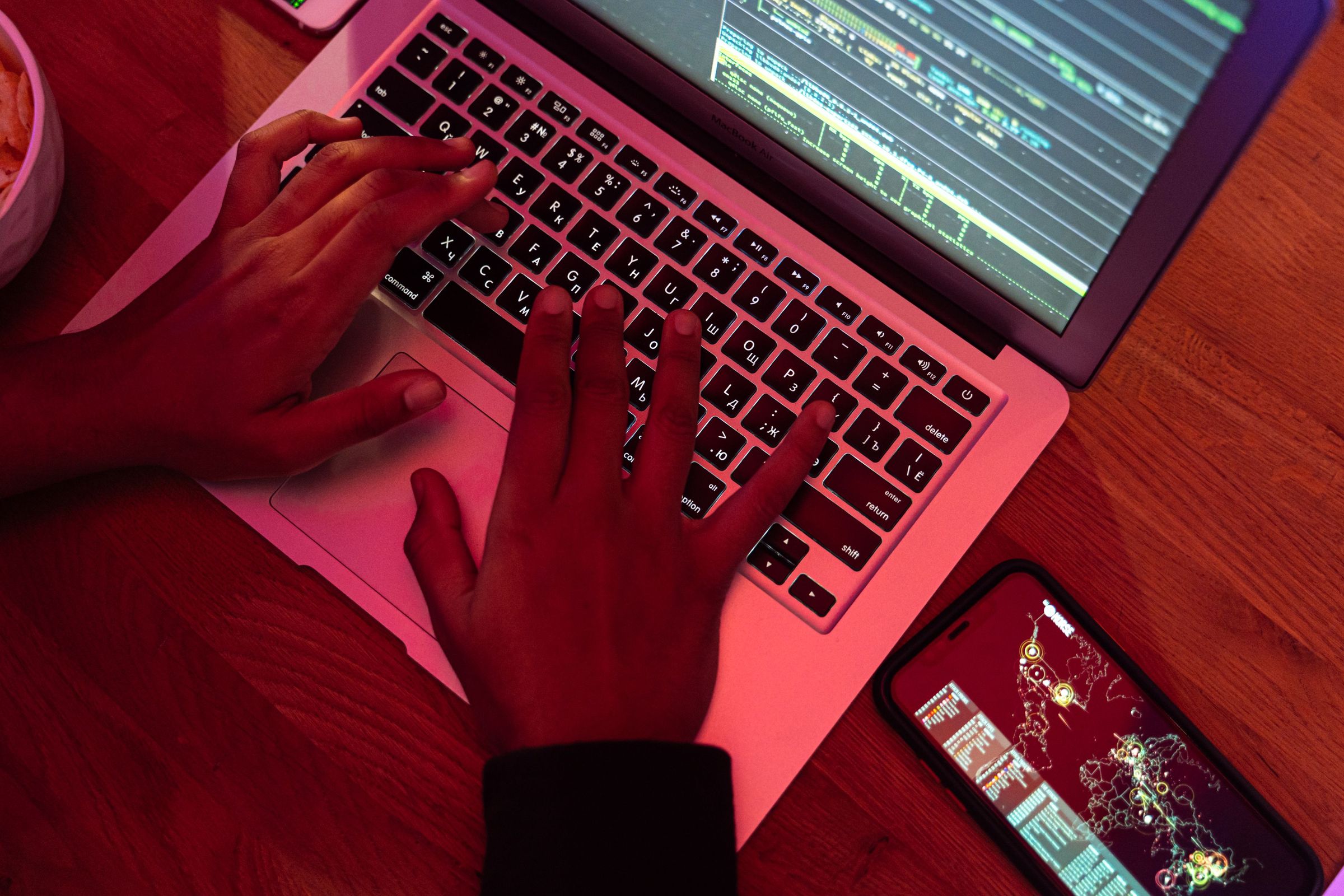 Hands typing on a laptop displaying software code