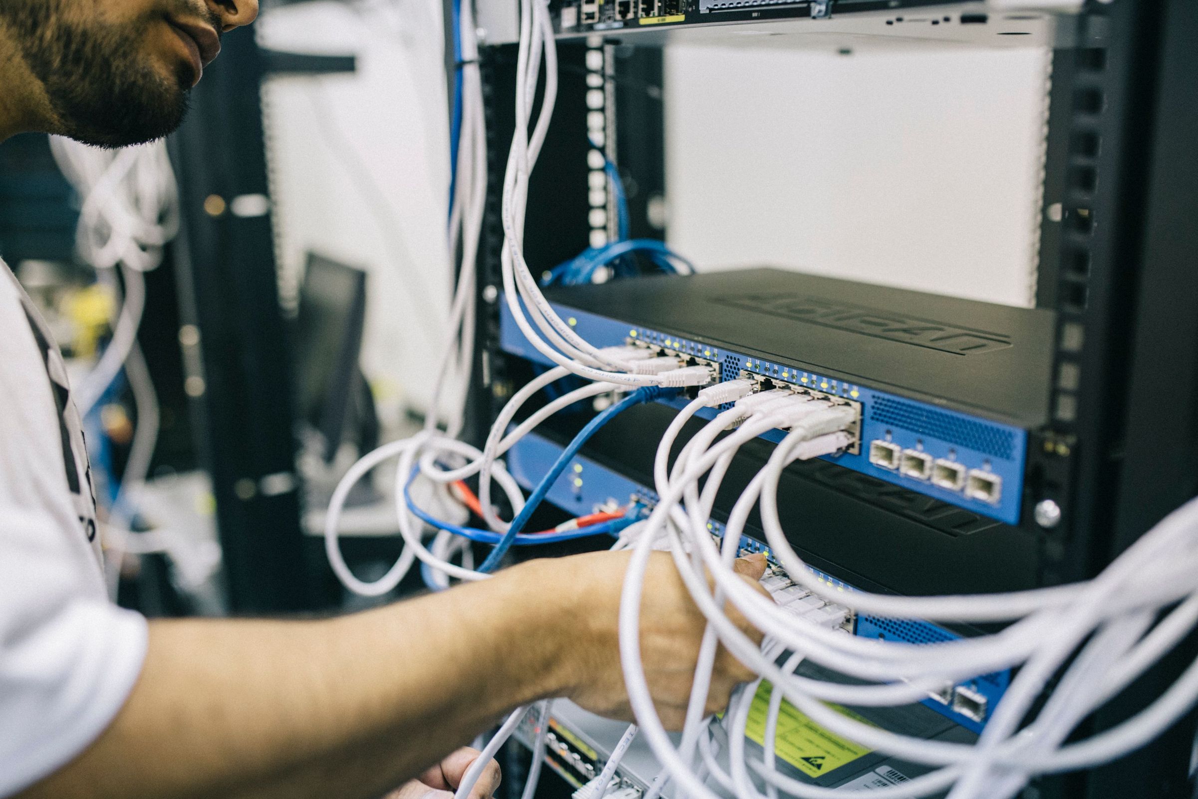 Person working on network cables in an equipment rack, a general infrastructure photograph