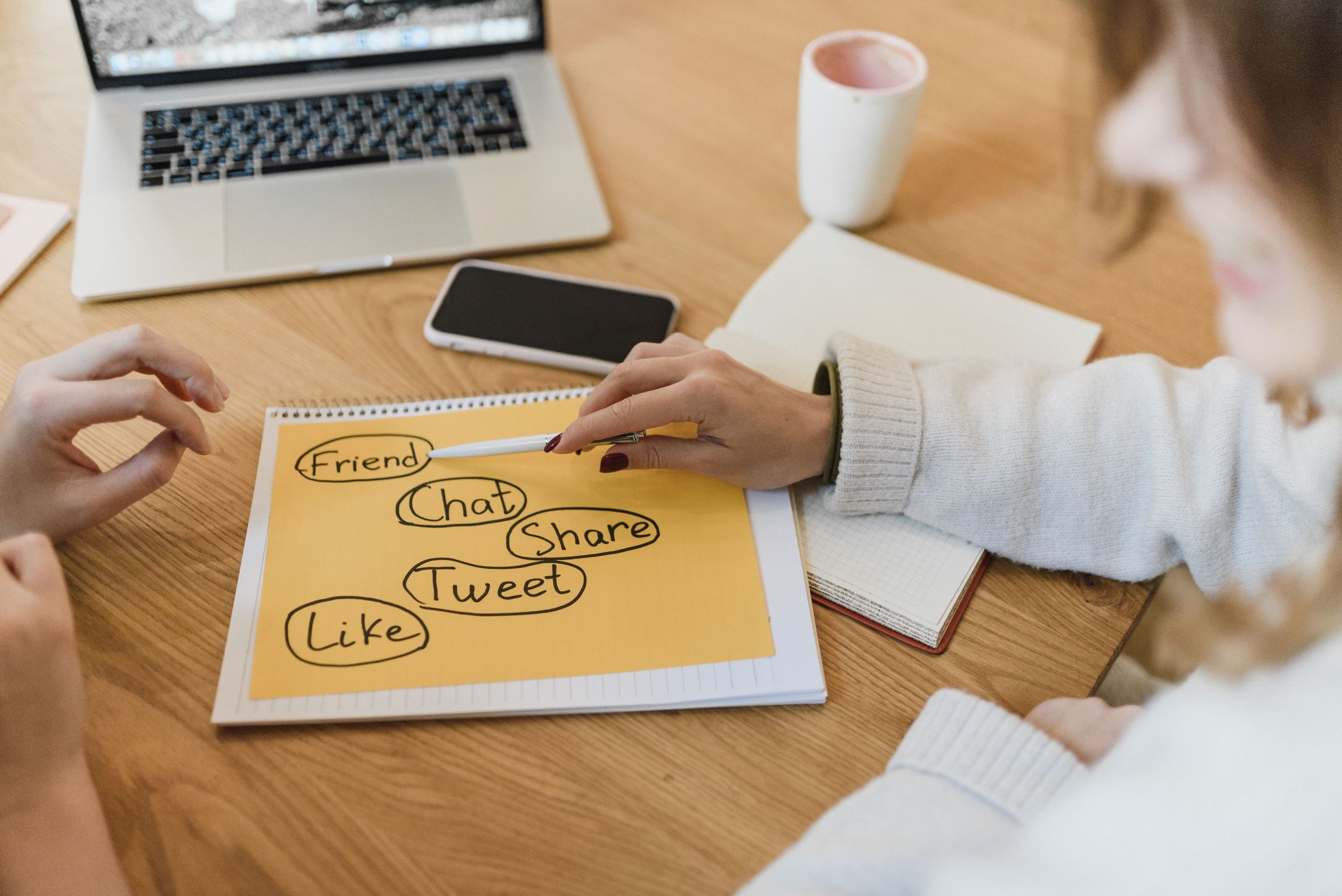 Planning social media content ideas on a notebook beside a laptop