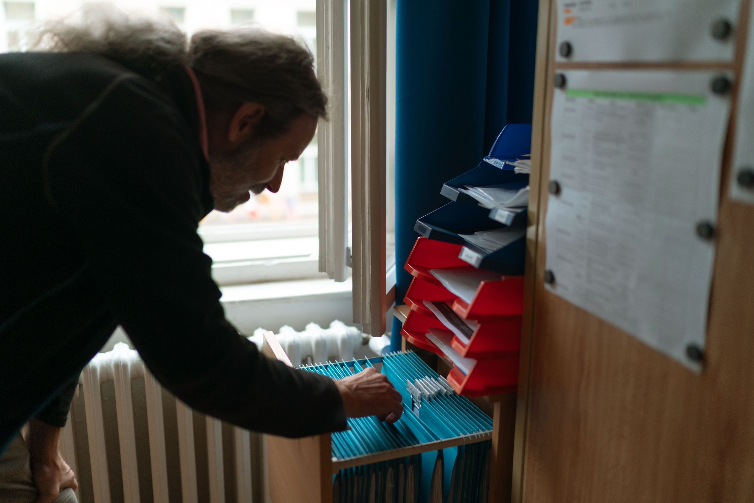 Person retrieves paper files from an office drawer in Prague