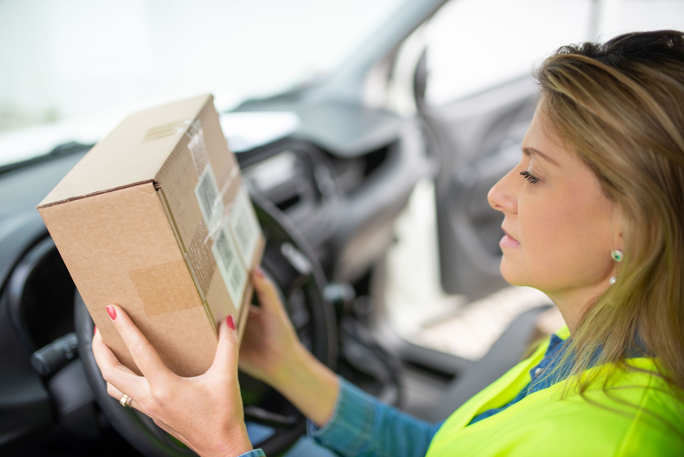 Courier in Portugal examining a parcel label inside a vehicle