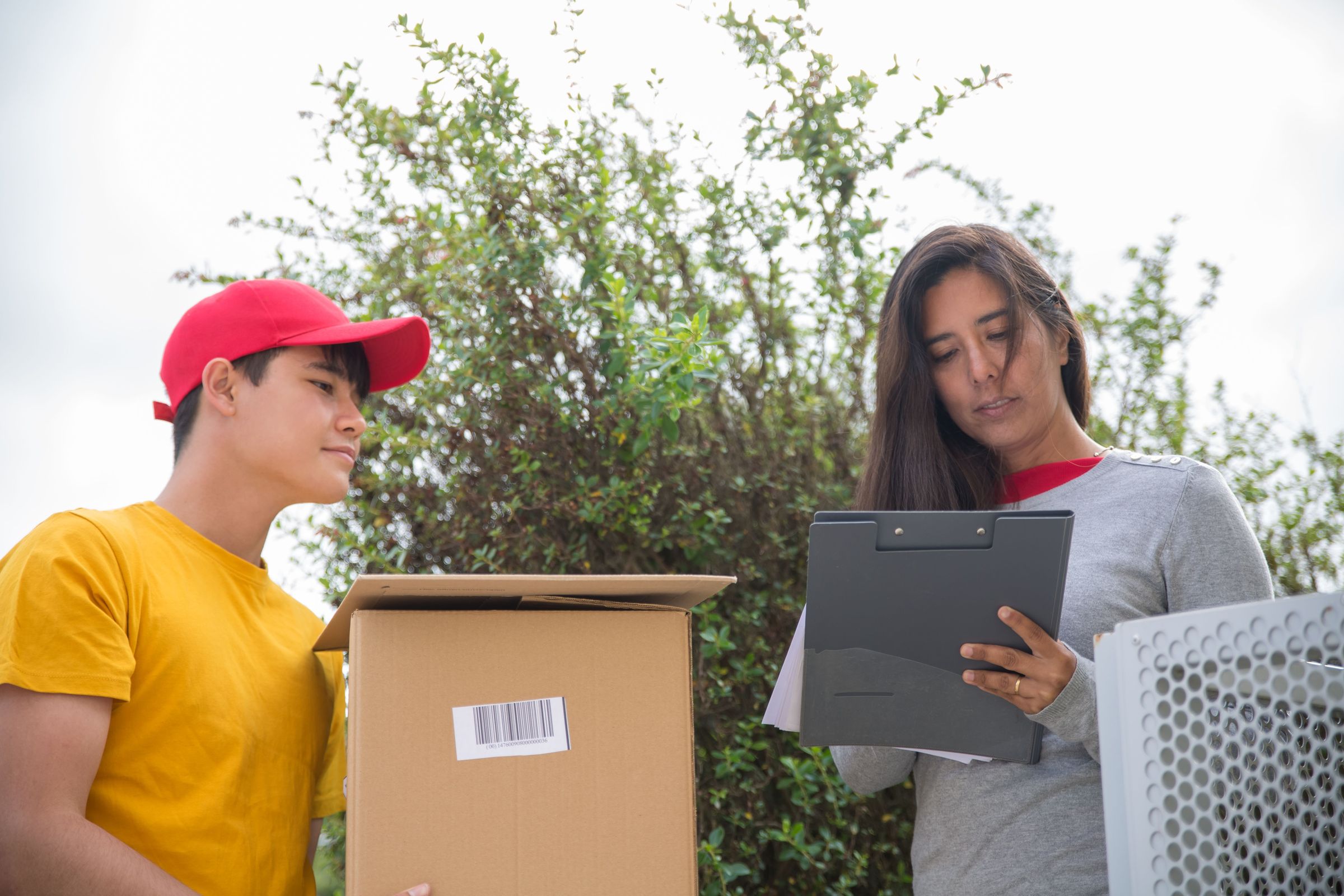 Recipient in Portugal reviewing a clipboard beside a courier and parcel