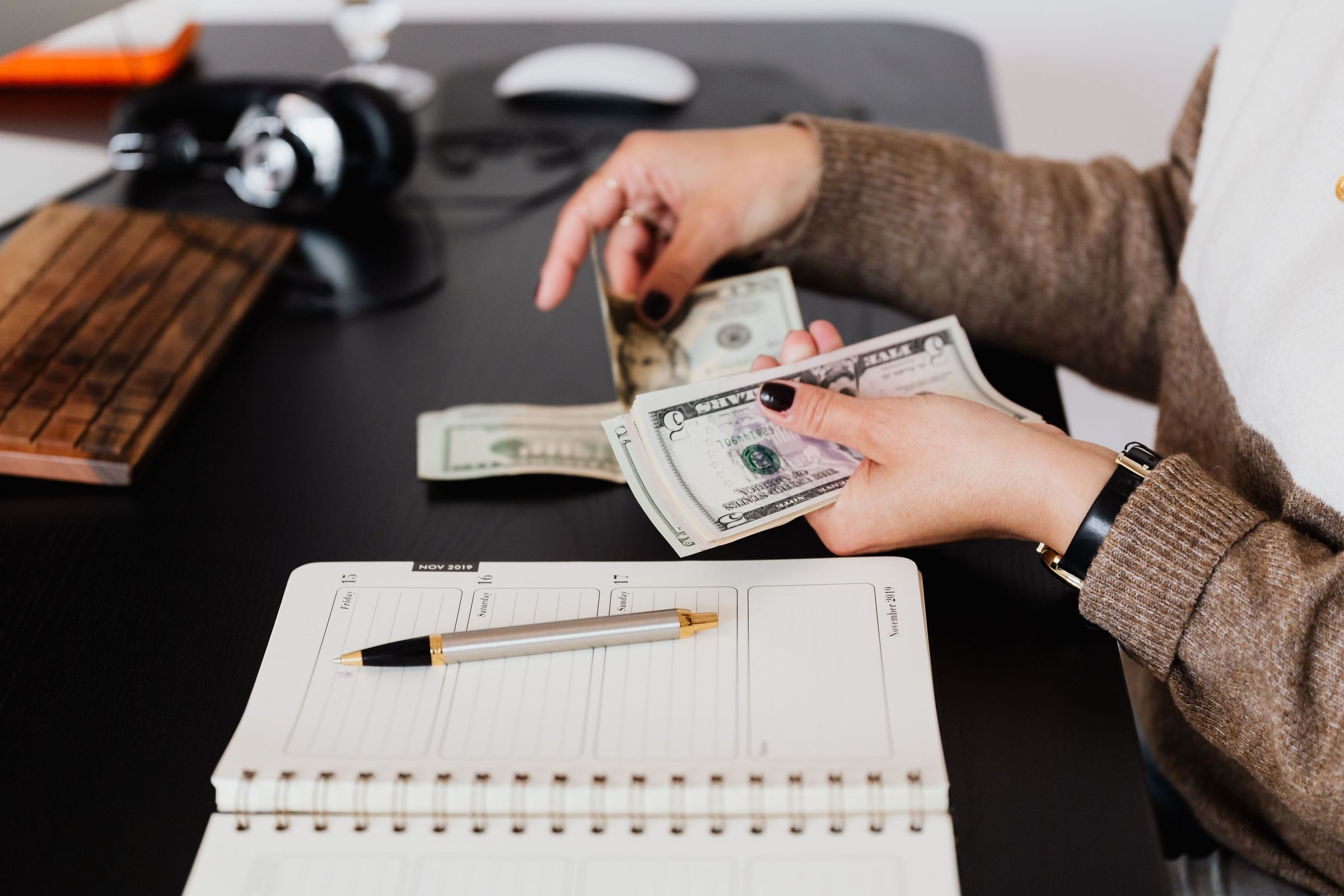 Counting banknotes beside a notebook and pen