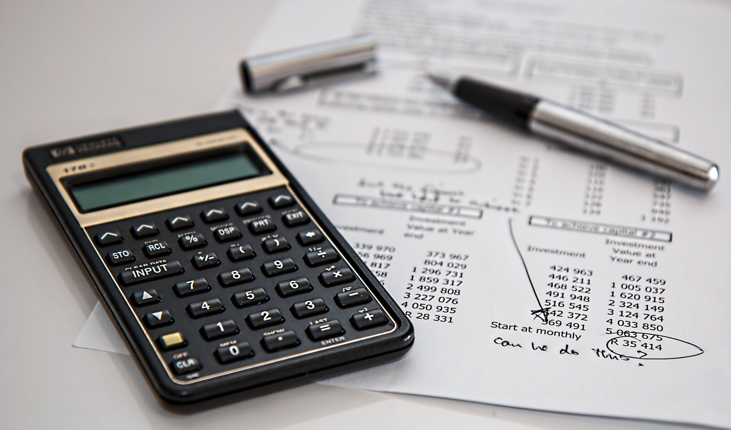 Calculator and pen beside printed financial figures