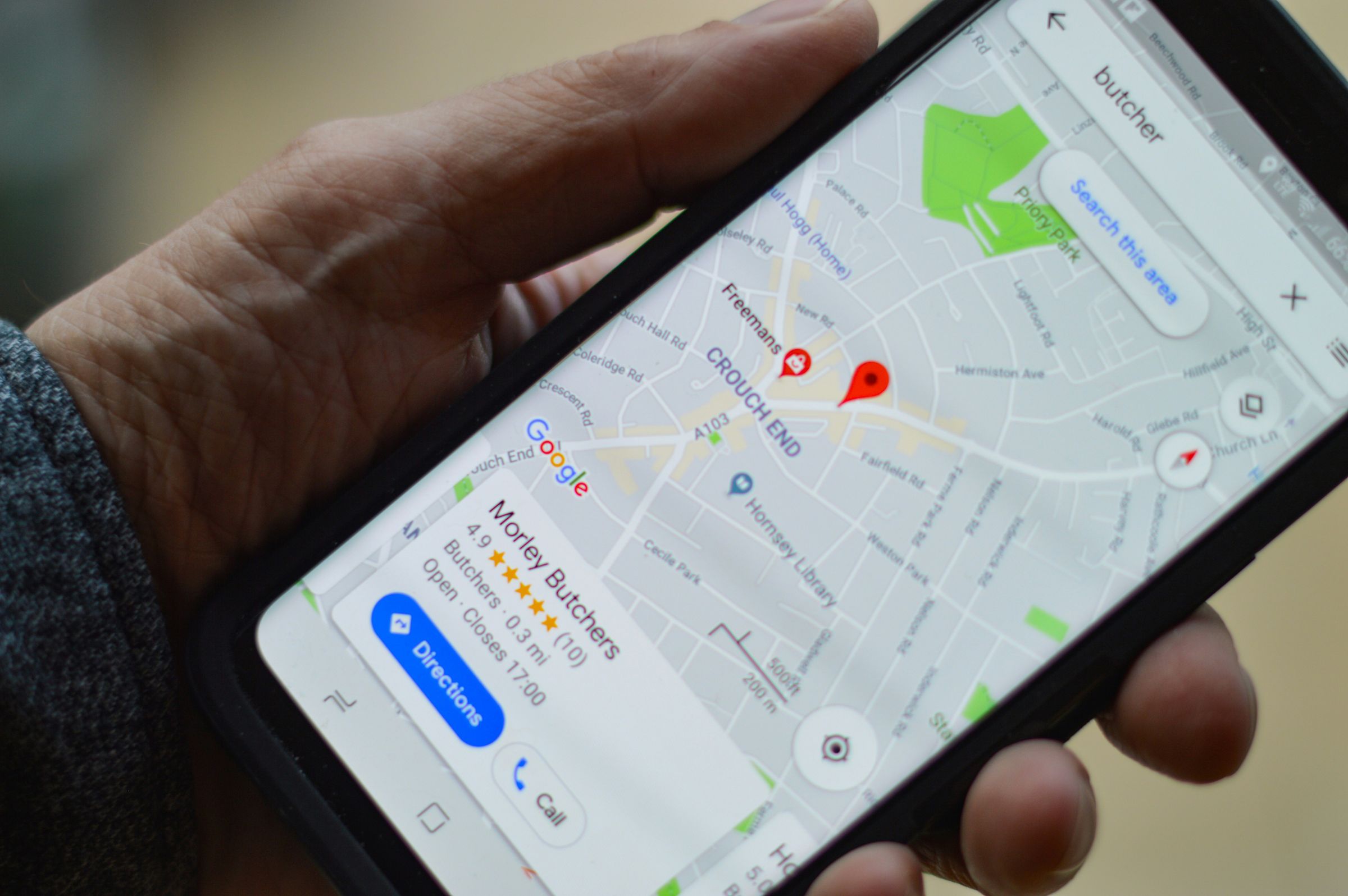 Hand holding a phone displaying a Google Maps business search