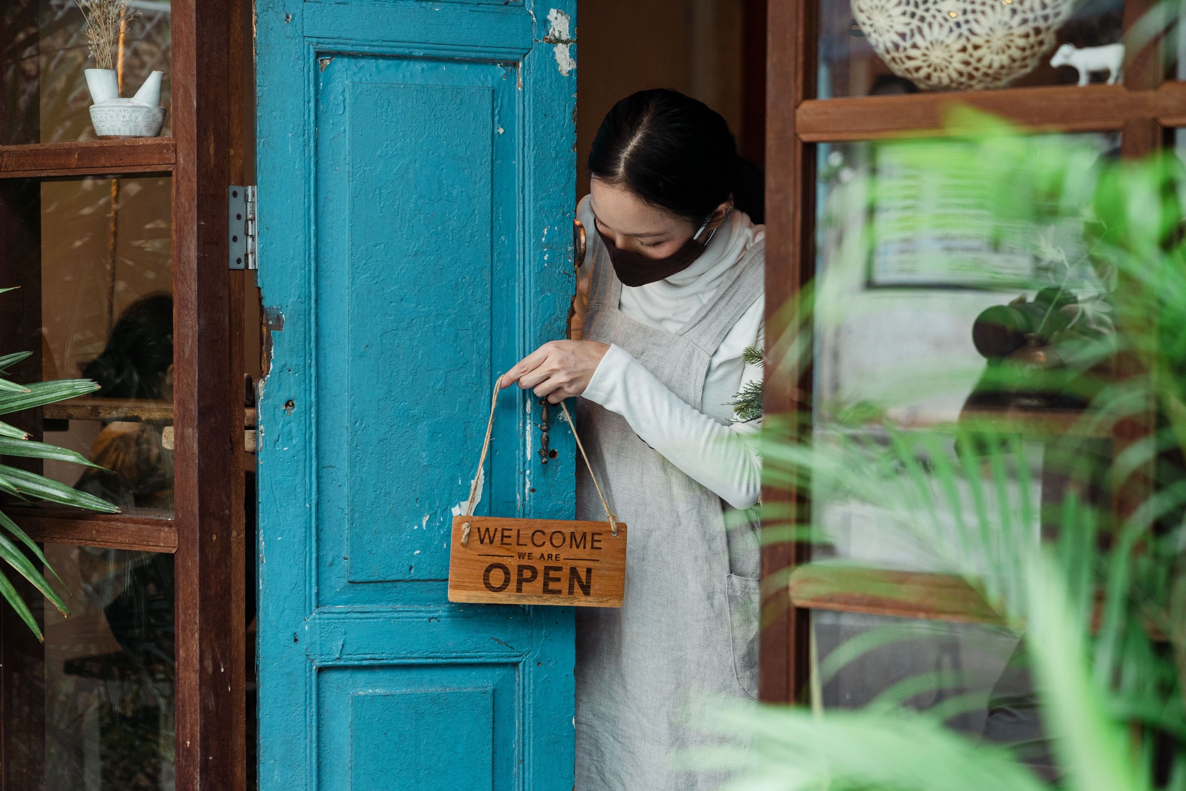 Person positioning an Open sign on a shop door