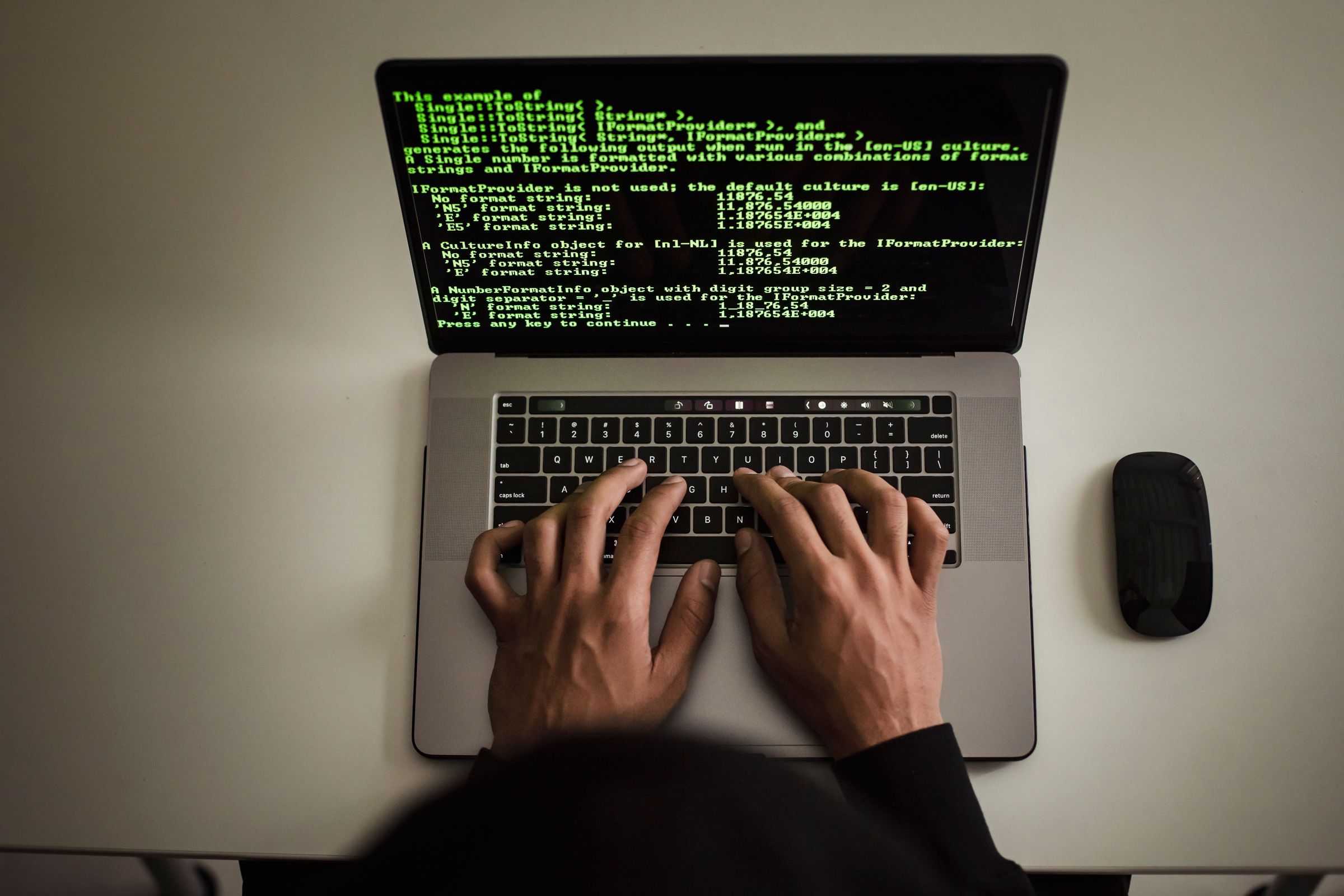 Hands typing on a laptop displaying programming text