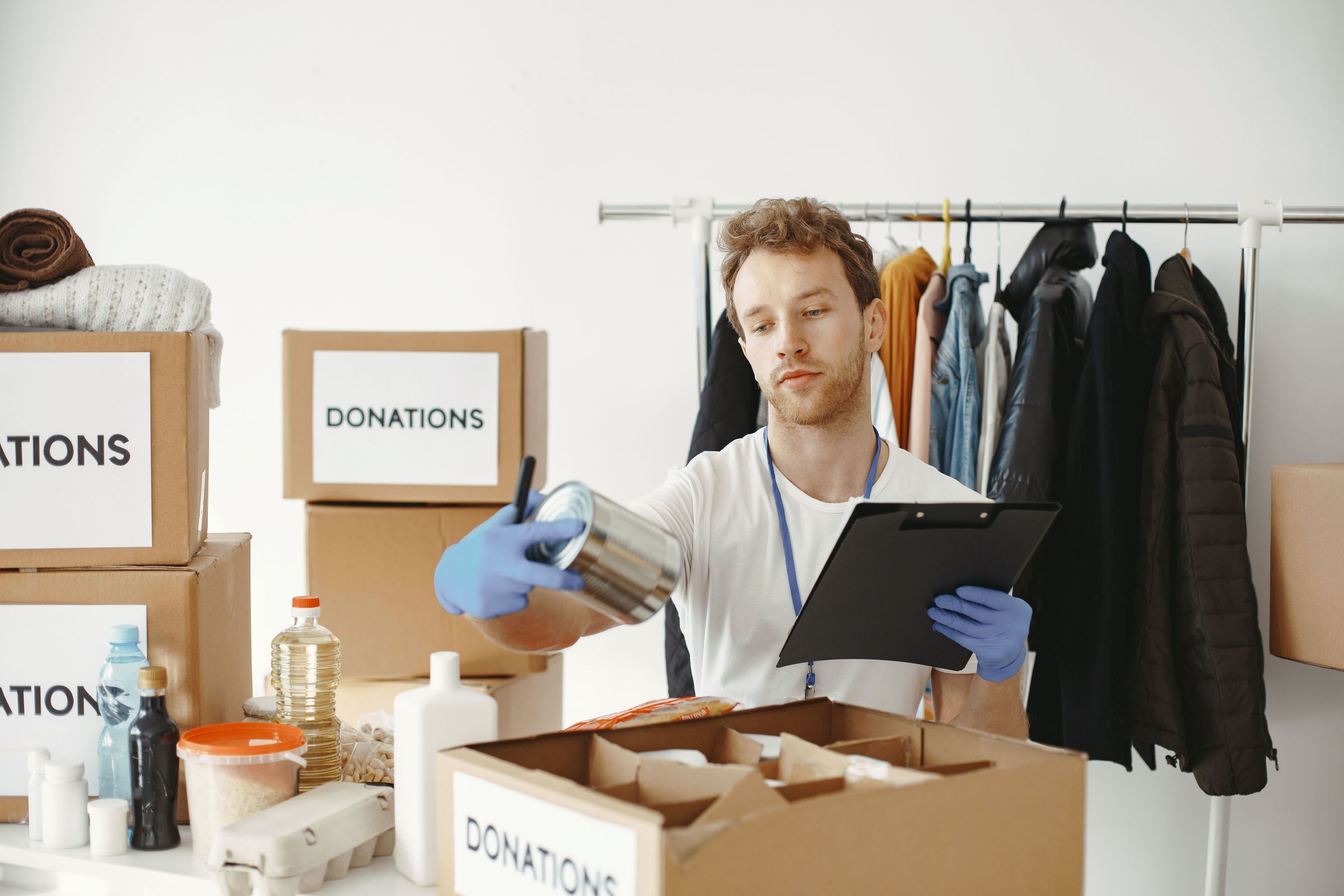 Volunteer inspecting a food tin beside donation boxes