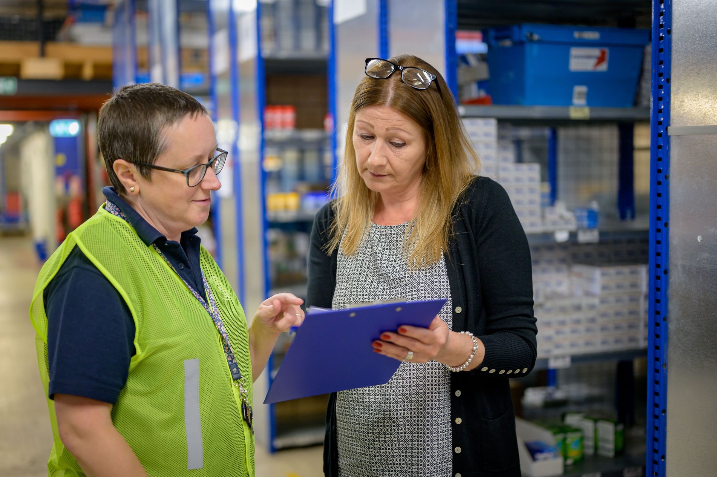 Reviewing a paper inventory checklist beside storage shelves