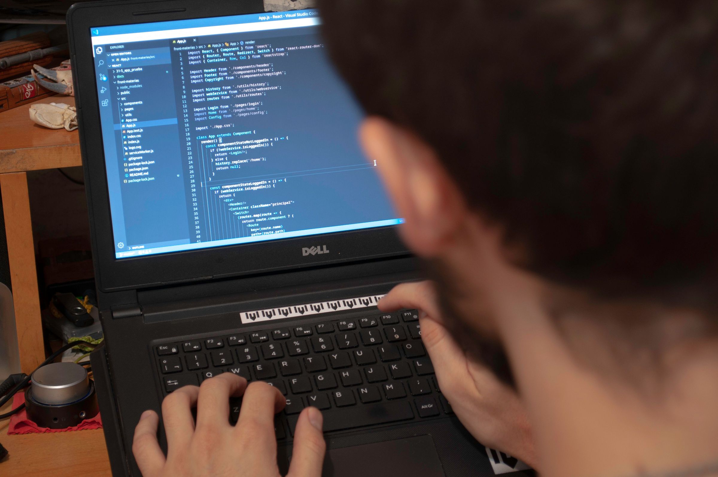 Hands using a laptop displaying programming text