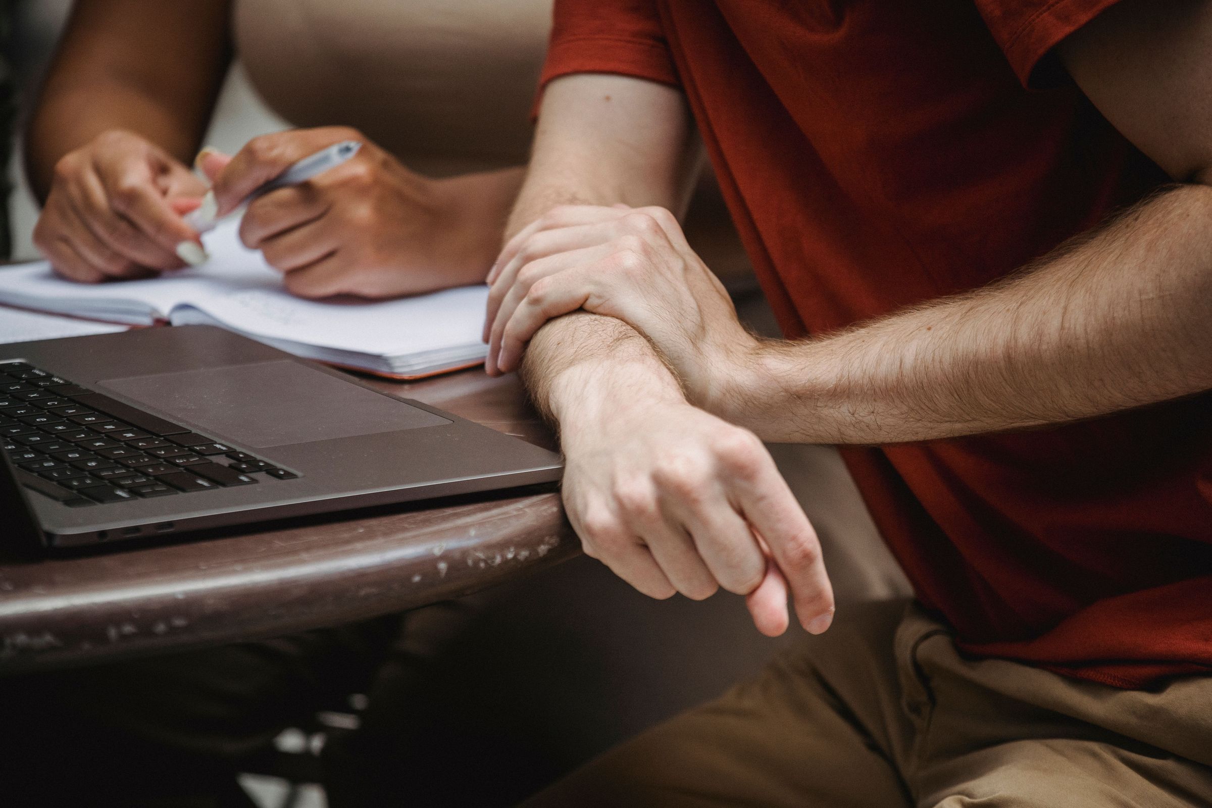 Two people using a notebook and laptop during a shared study session