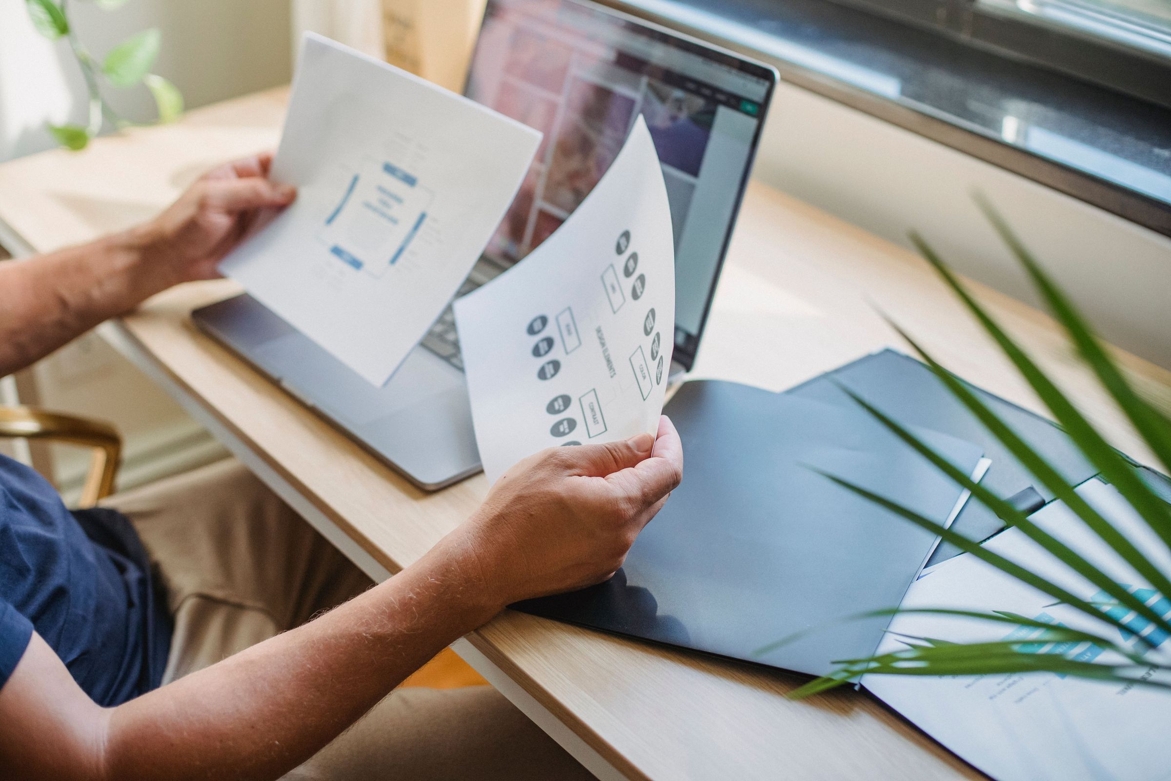 Reviewing interface-design documents beside a laptop