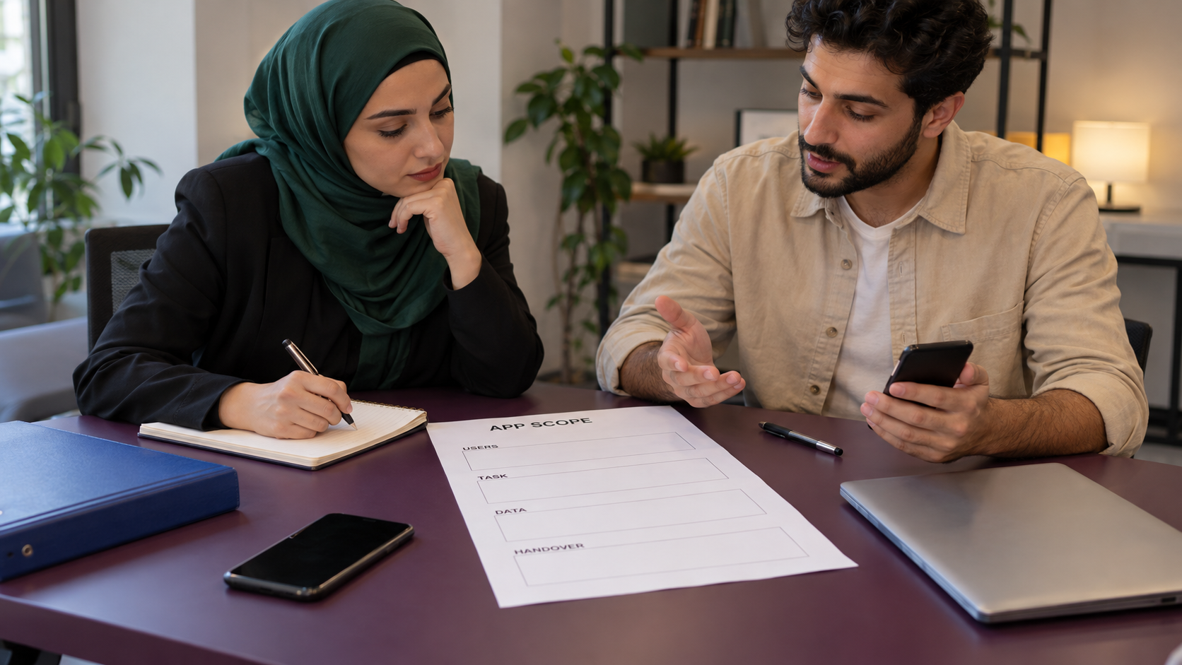 مشهد توضيحي لمناقشة نطاق تطبيق بأوراق فارغة وهاتف مطفأ