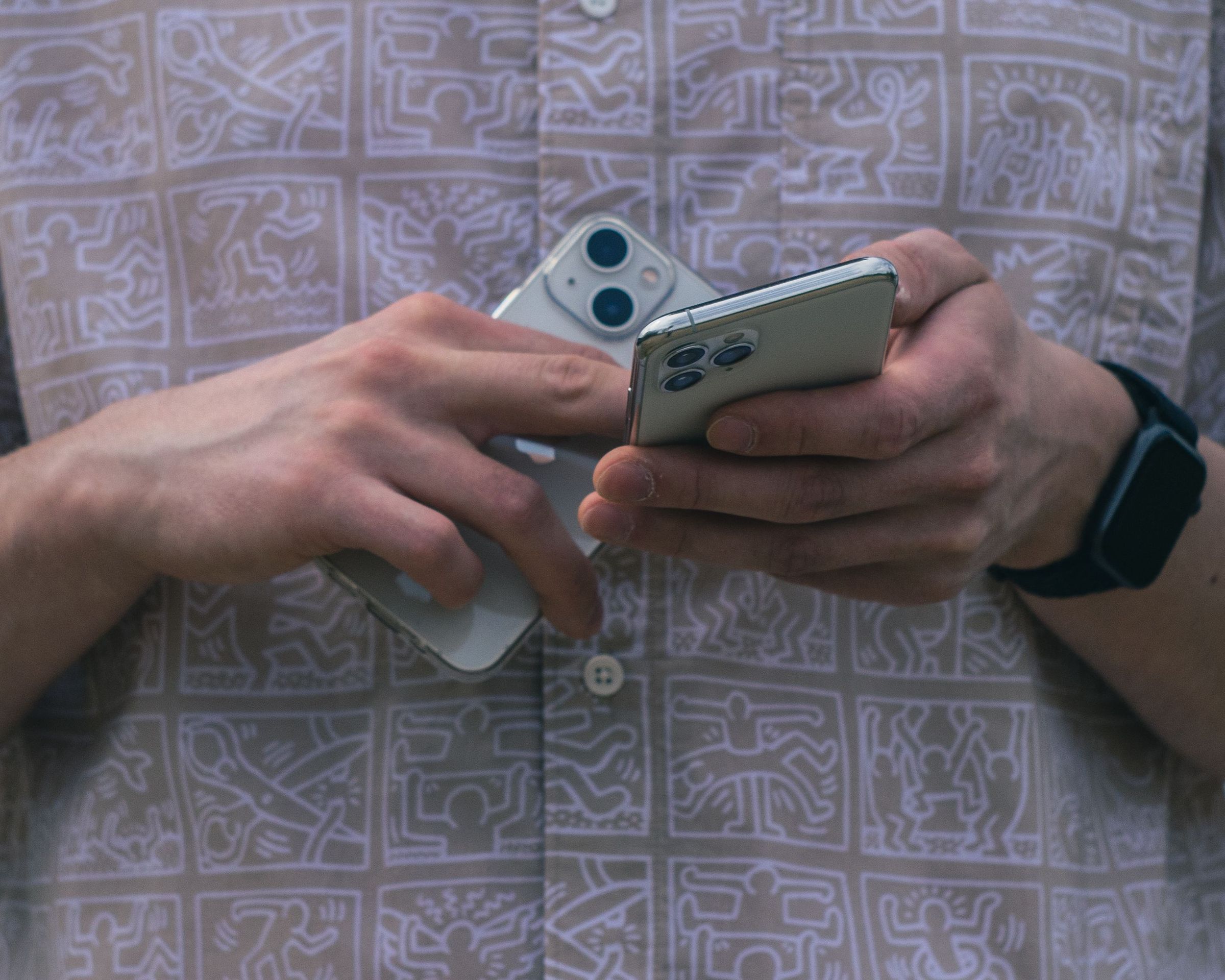 Hands holding two phones with the rear cameras of each device visible