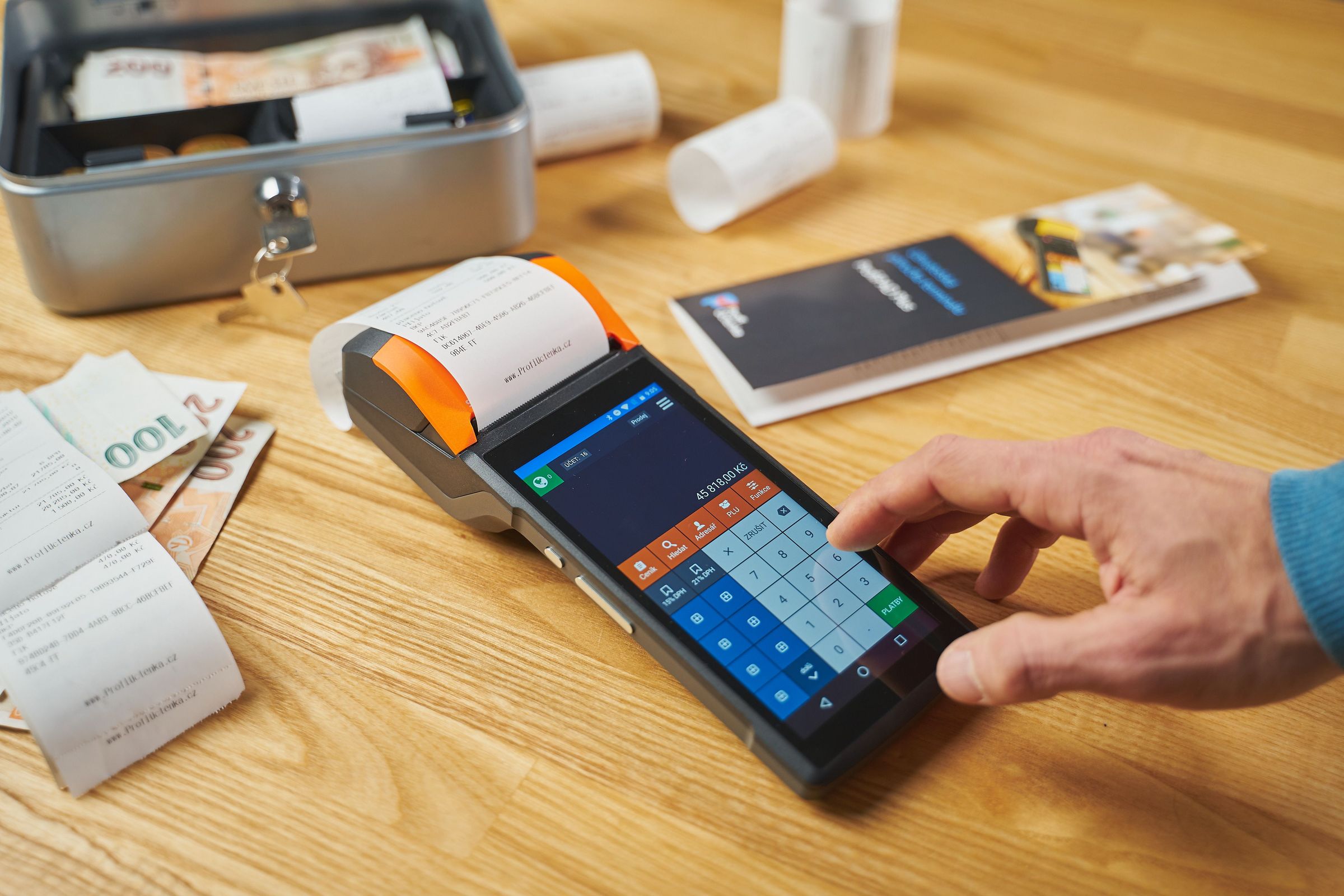Entering an amount on an electronic cash register beside receipts and cash
