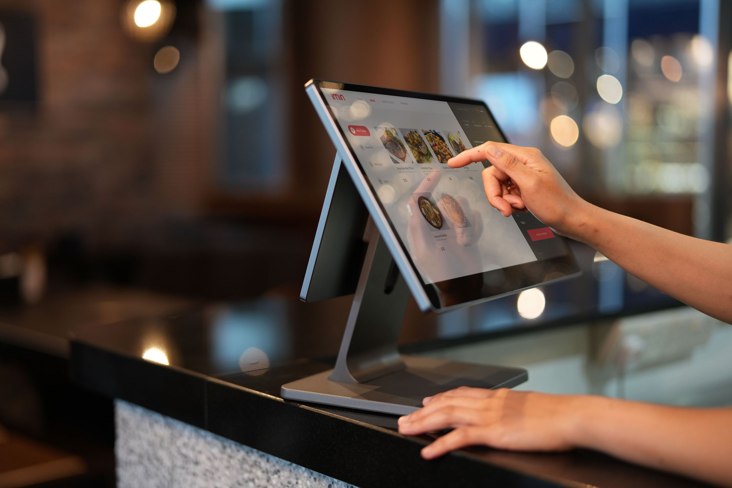 Person using a POS screen with product images and an order panel