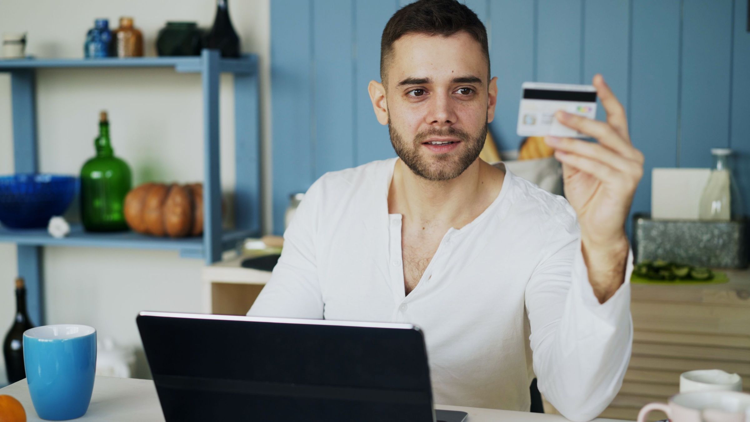 Person holding a card in front of a laptop at a table