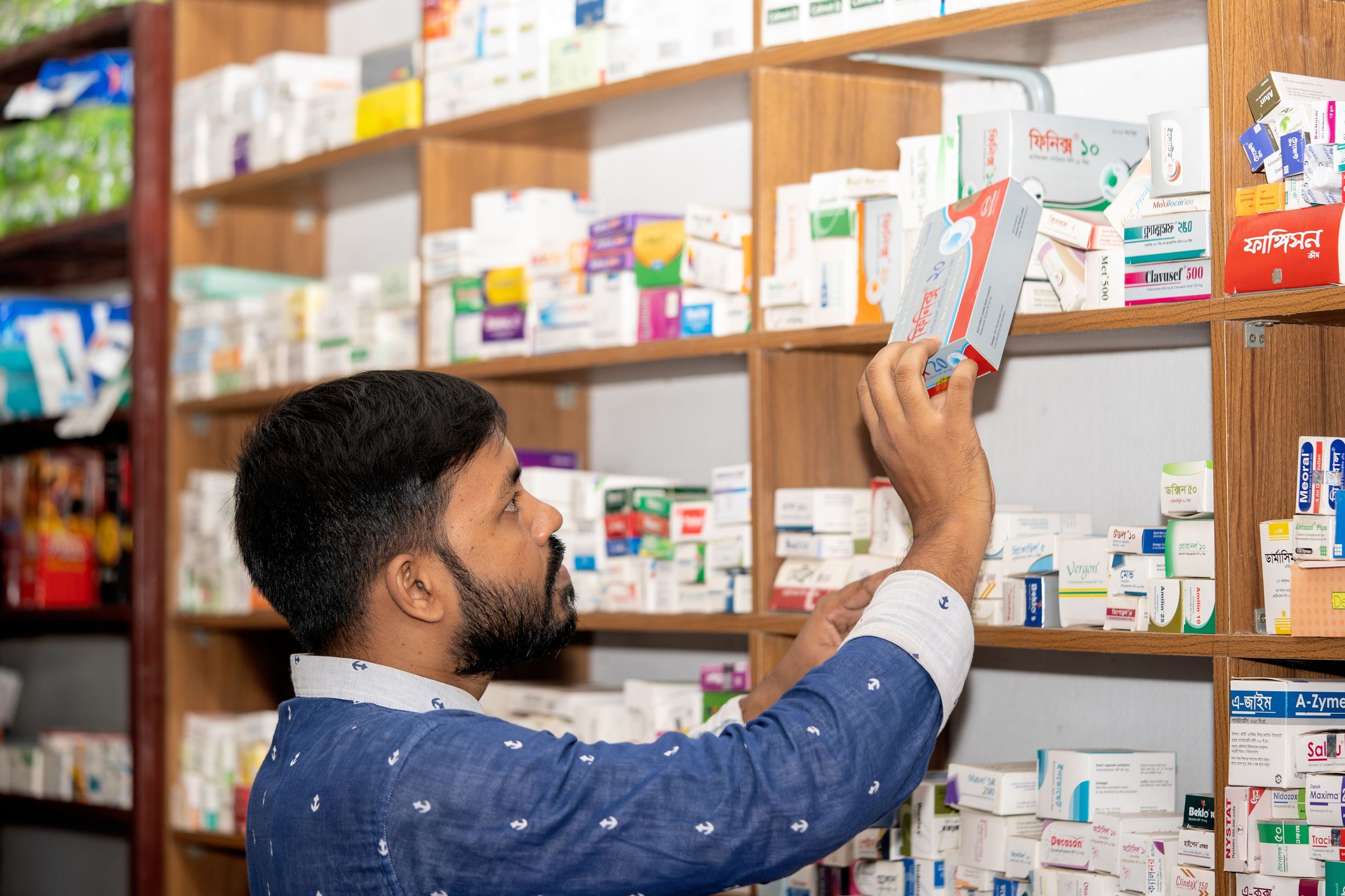 Medicine pack being handled at pharmacy shelves in Bangladesh