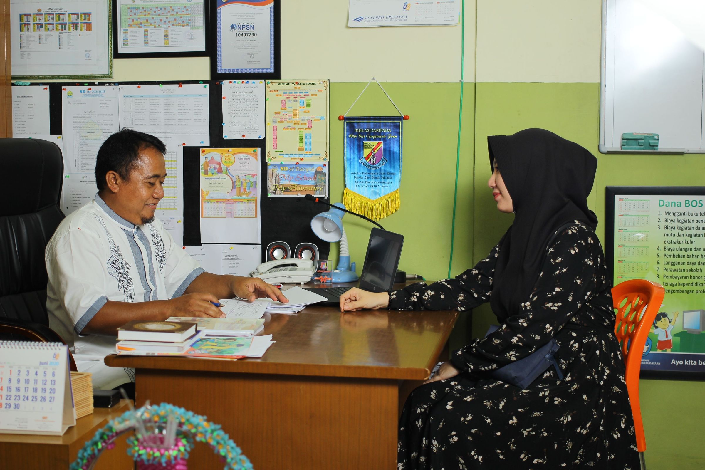 Parent and school official discussing paperwork in an Indonesian office