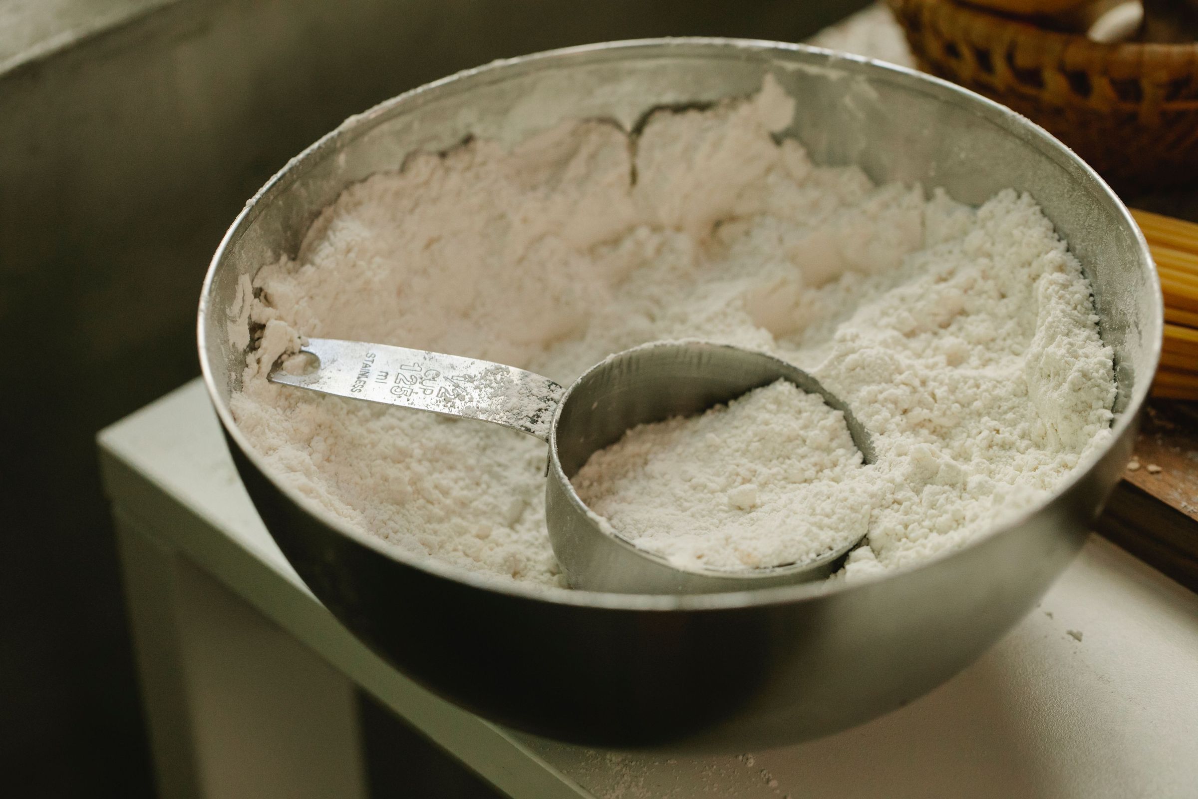 Flour bowl and metal measuring cup illustrating volume rather than a verified flour weight