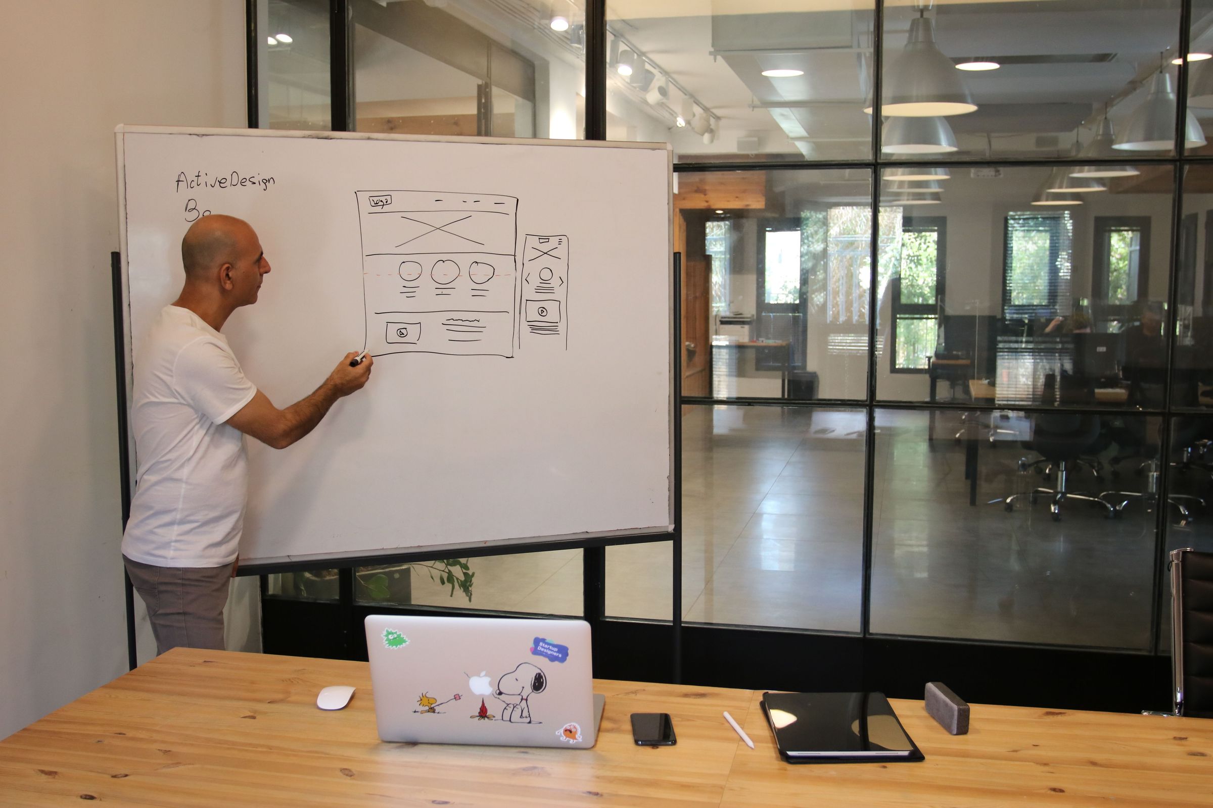 Designer sketching desktop and mobile website layouts on a whiteboard