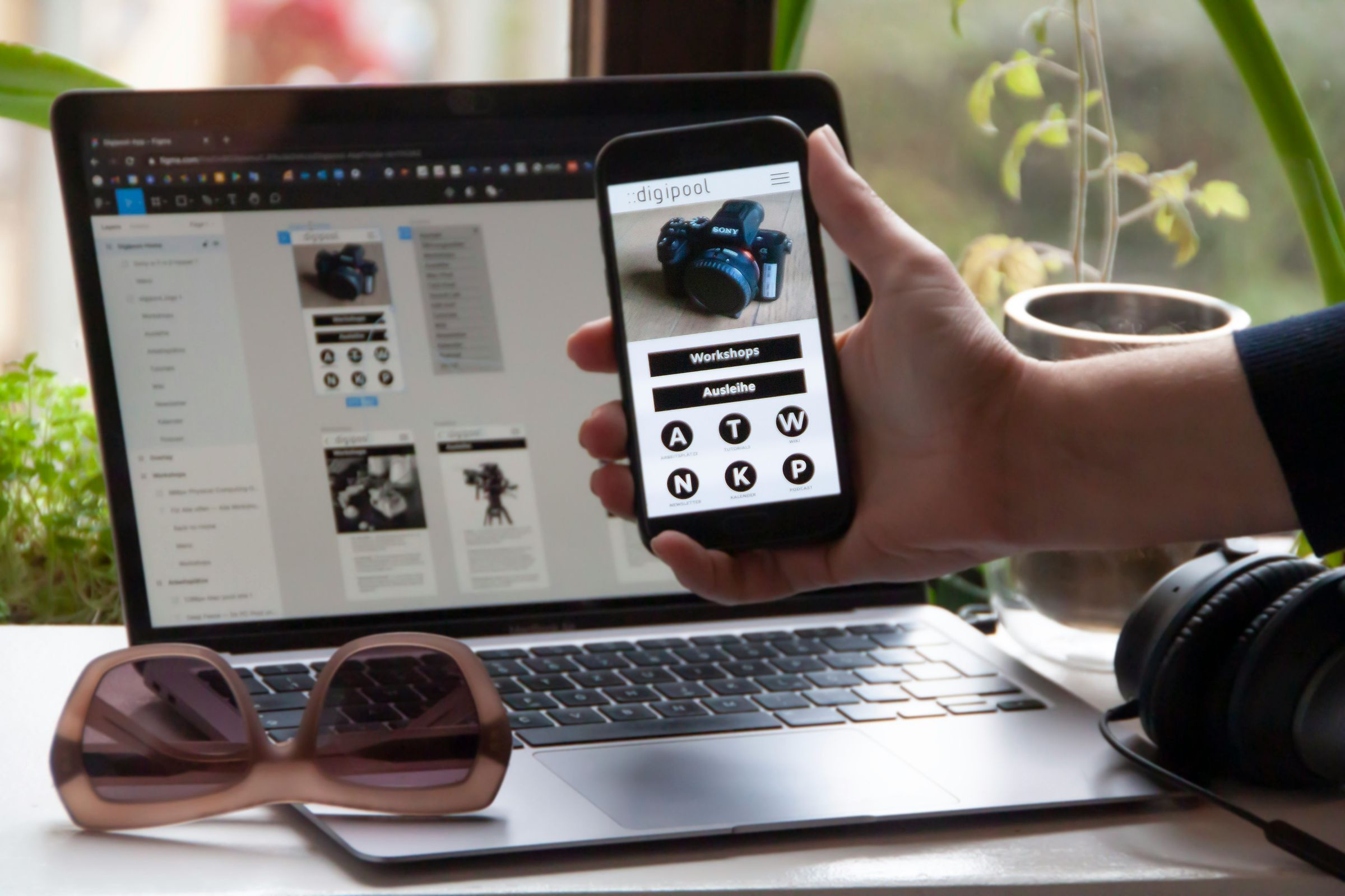 Phone displaying a website interface in front of its design on a laptop