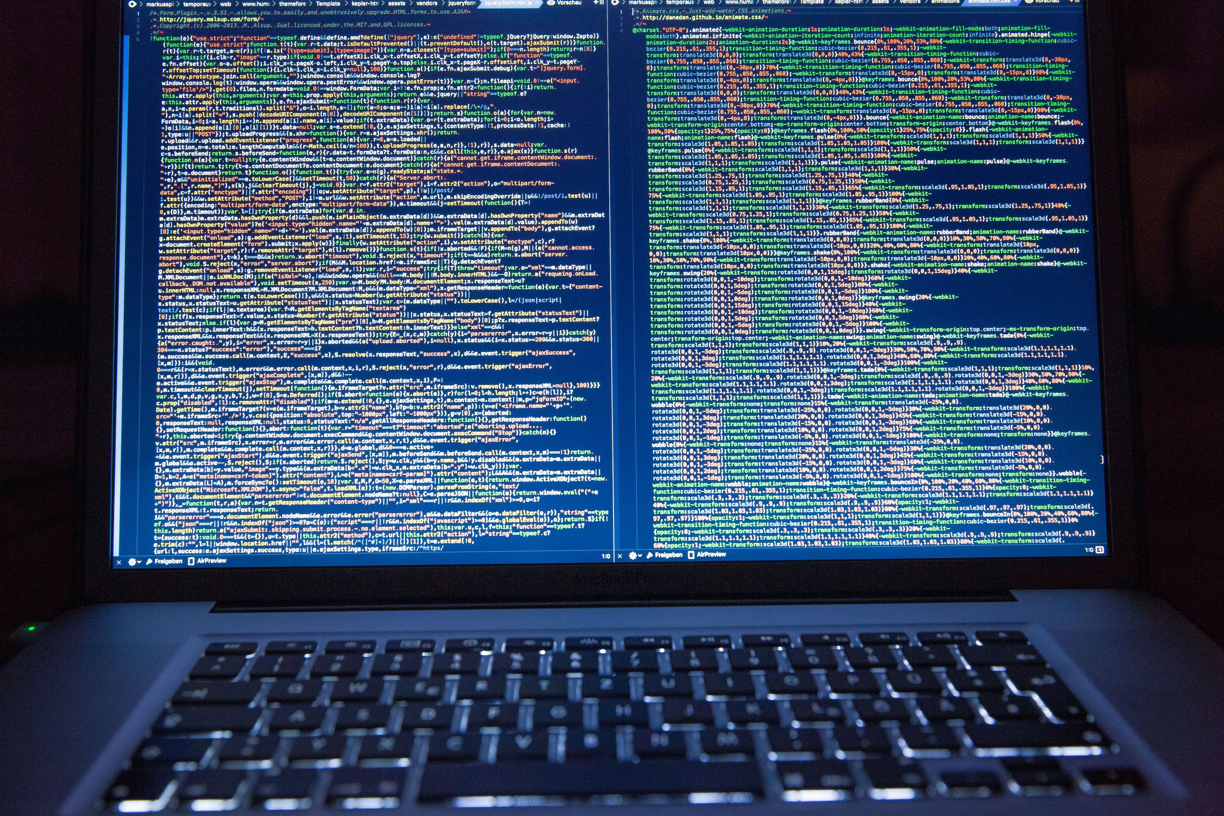 Laptop displaying JavaScript and CSS files in a code editor