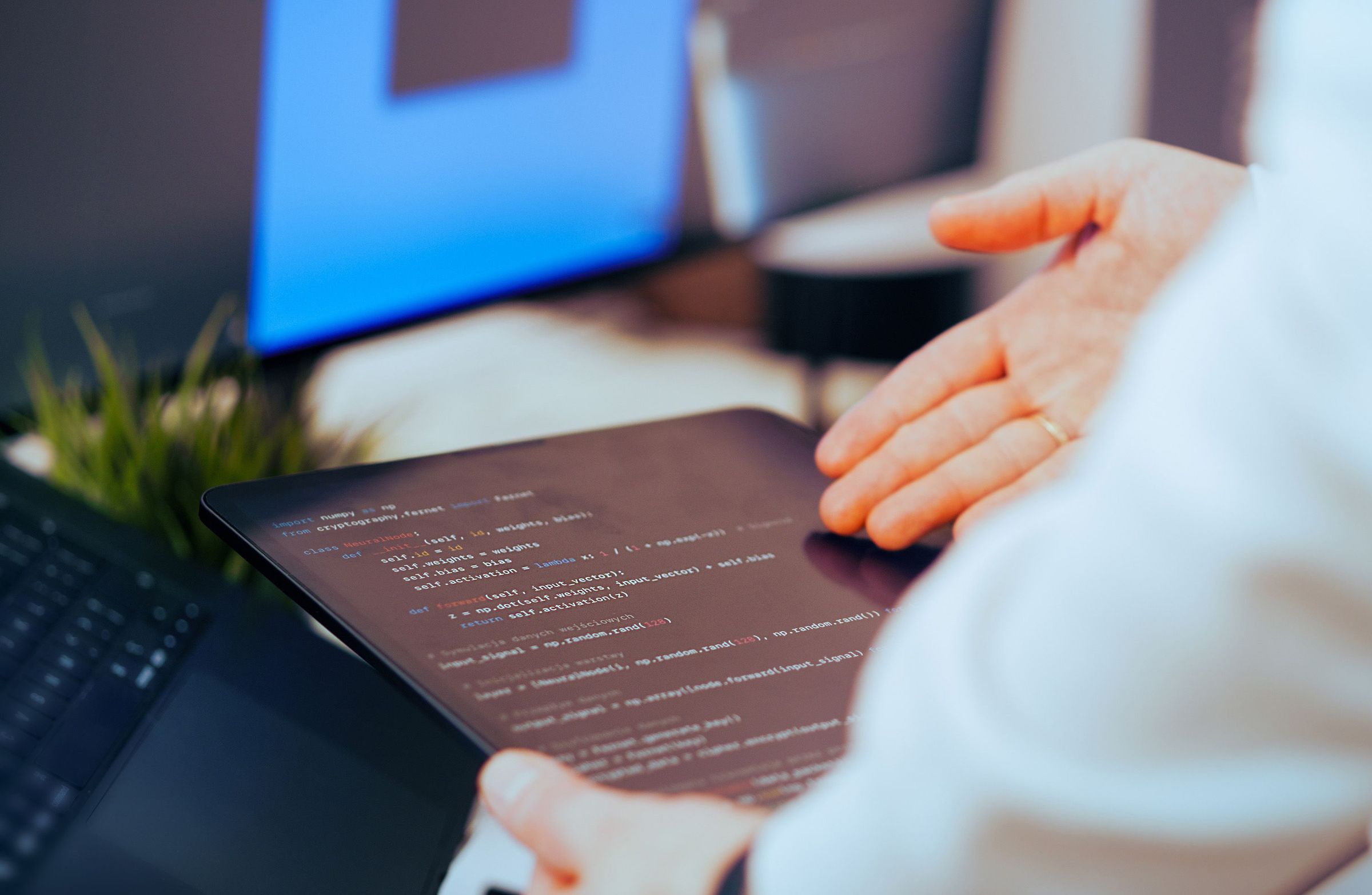 Person reviewing code on a tablet beside a computer