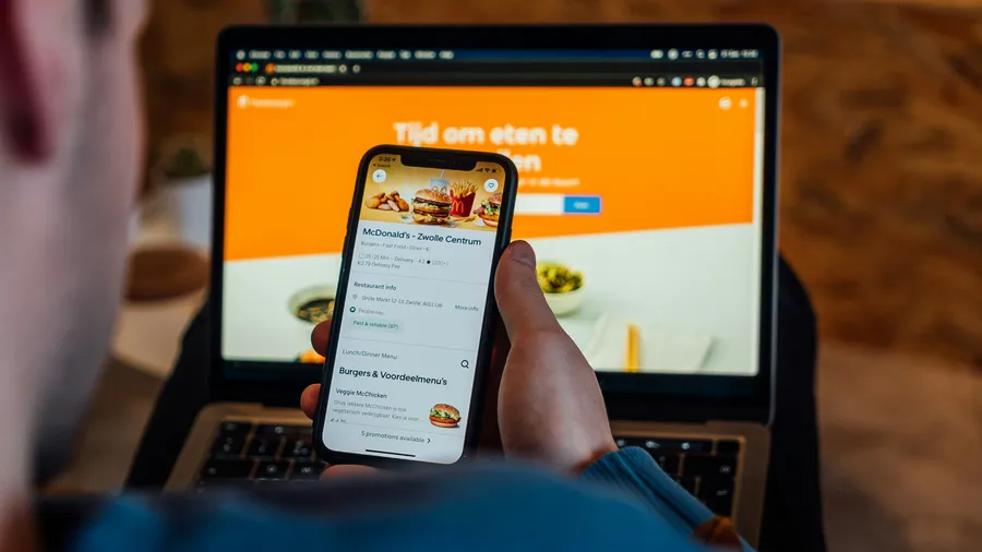 Browsing a restaurant menu on a phone in front of an online food-ordering website in the Netherlands