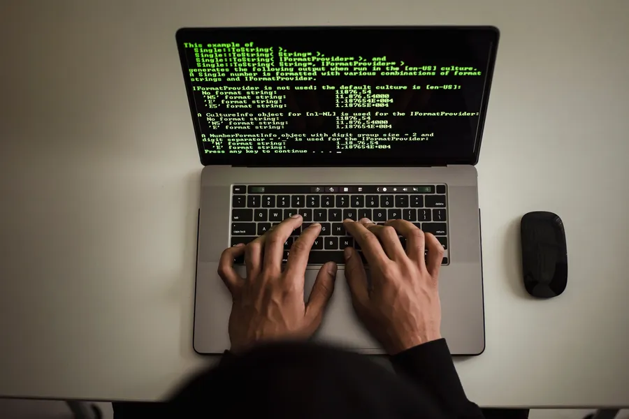 Hands typing on a laptop displaying programming text