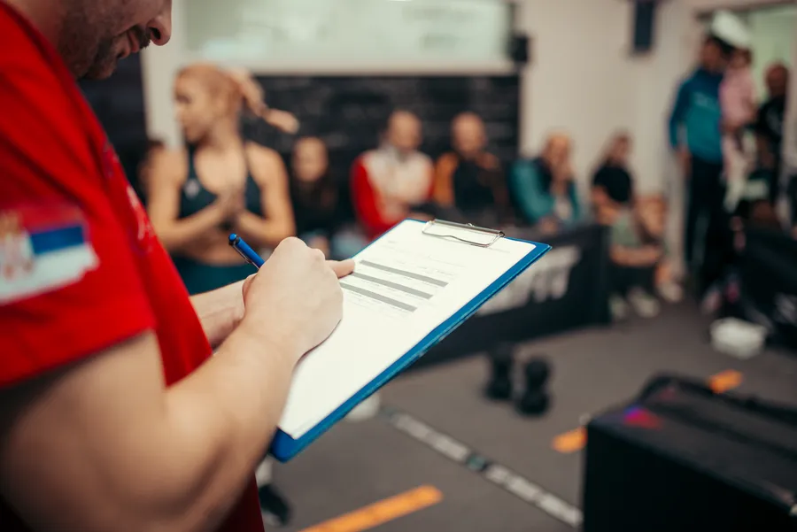 Coach writing on a clipboard in a training gym