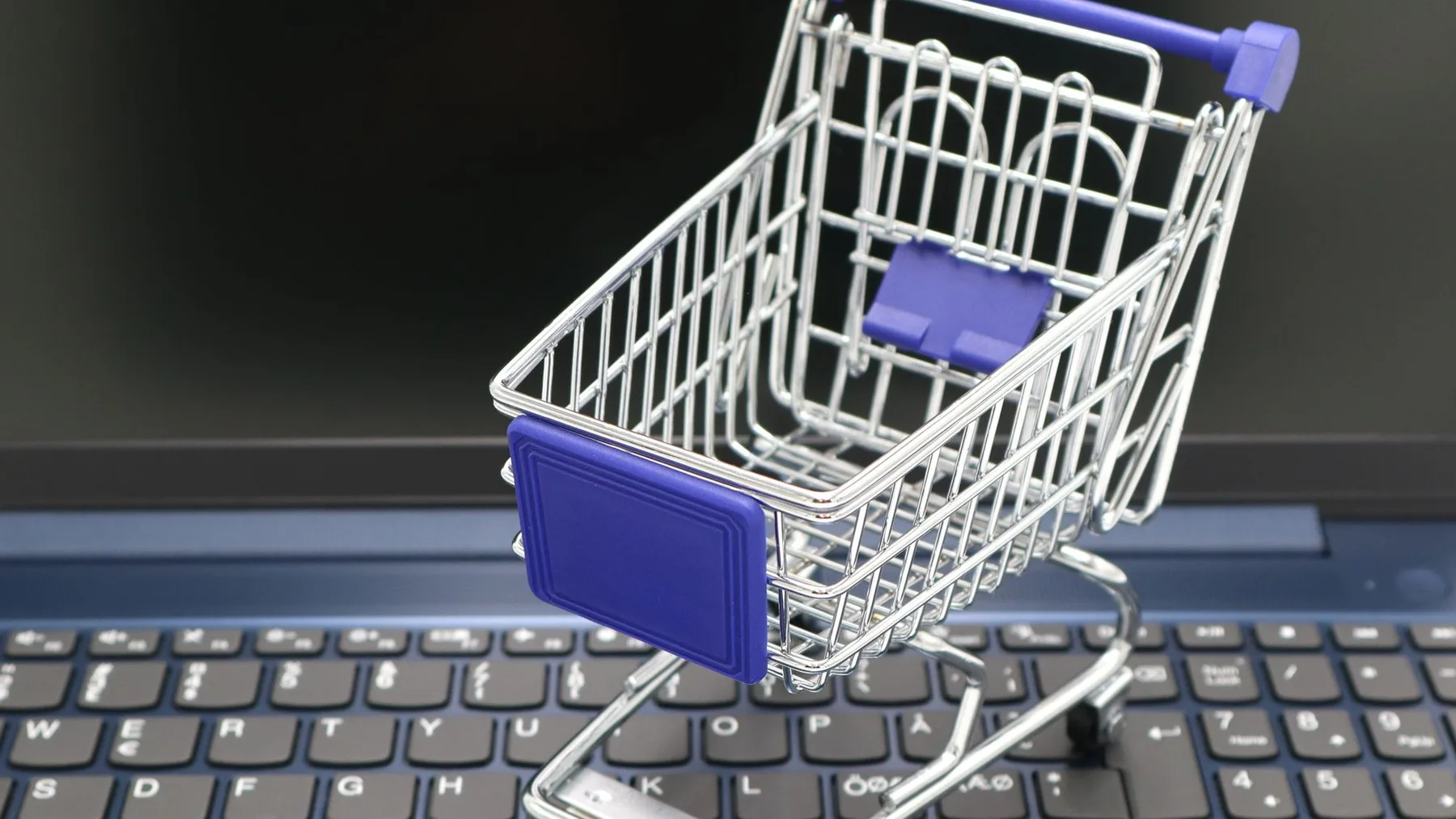 Miniature shopping cart on a keyboard representing ecommerce platform selection